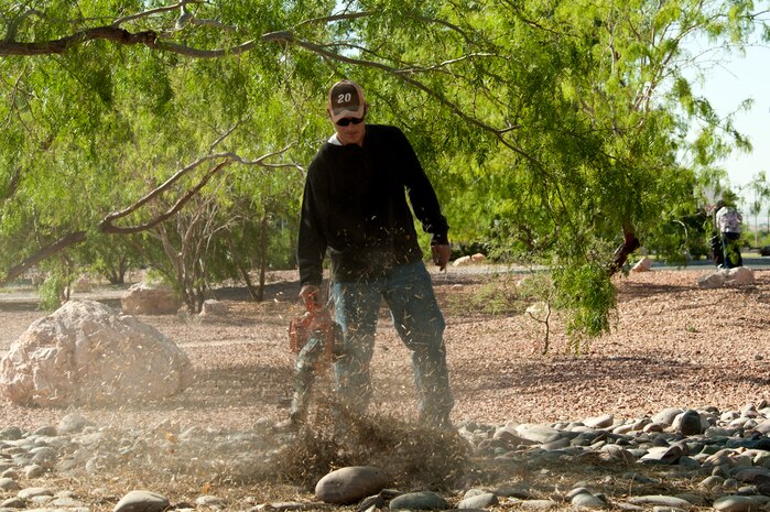 Master Sgt. Dana Vaughan, 99th Civil Engineer Squadron environmental element NCO in charge, uses a leaf blower to clear leafs from a decorative rock area of the Maj. Gen. Billy McCoy Environmental Grove during a group cleanup event April 24, 2014 at Nellis Air Force Base, Nev. Decomposing leafs can become a breeding ground for unwanted bugs. (U.S. Air Force photo by Airman 1st Class Timothy Young)