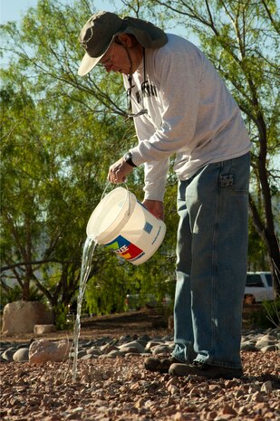 Bill Filipowski, master gardener, waters a plant during a Maj. Gen. Billy McCoy Environmental Grove cleanup event April 24, 2014 at Nellis Air Force Base, Nev. The grove was developed as a place for Airmen to go and relax. (U.S. Air Force photo by Airman 1st Class Timothy Young)