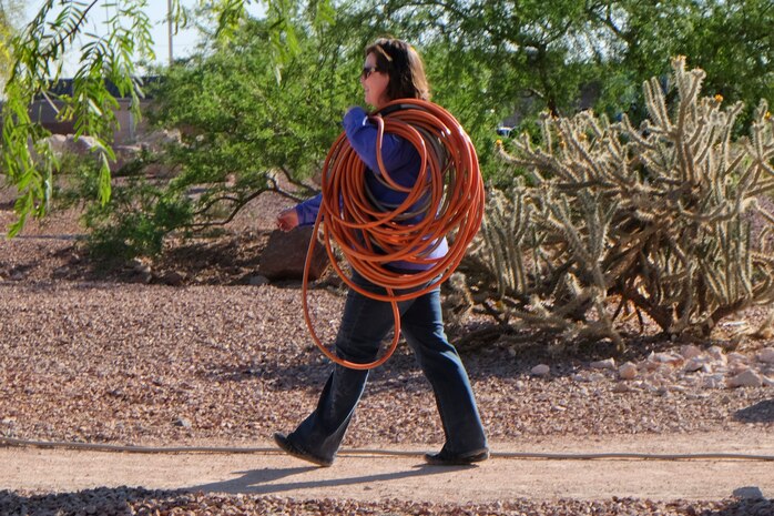 Ann Bedlion, 99th Civil Engineer Squadron natural resource manager, carries a garden hose to water newly planted trees during the Earth Day clean up at the Maj. Gen. Billy McCoy Environmental Grove April 24, 2014 at Nellis Air Force Base, Nev.  99 CES members and volunteers come to the environmental grove every Earth Day to clean up the park. (U.S. Air Force photo by Lorenz Crespo)
