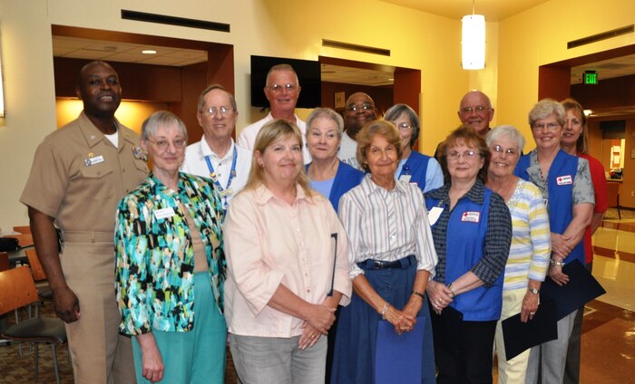 The American Red Cross volunteers at Naval Health Clinic Charleston were honored for their contributions during a recognition ceremony April 29, 2014, at the clinic on Joint Base Charleston – Weapons Station. NHCC currently has 18 American Red Cross volunteers who donate approximately 4,500 hours of service annually. Back row: NHCC Commanding Officer Capt. Marvin Jones, William Mehard, James Crane, Stanley Nelson, James Tyrrell, Jeanne Carmichael; center row: Eileen Hadbabny, Reggie Gardner, Paulette Blew, Barb Tyrrell, Cheryl Harris; front row: Lois Neal, Carol Cramer, Sharon Monheit. (U.S. Navy photo/Kris Patterson)