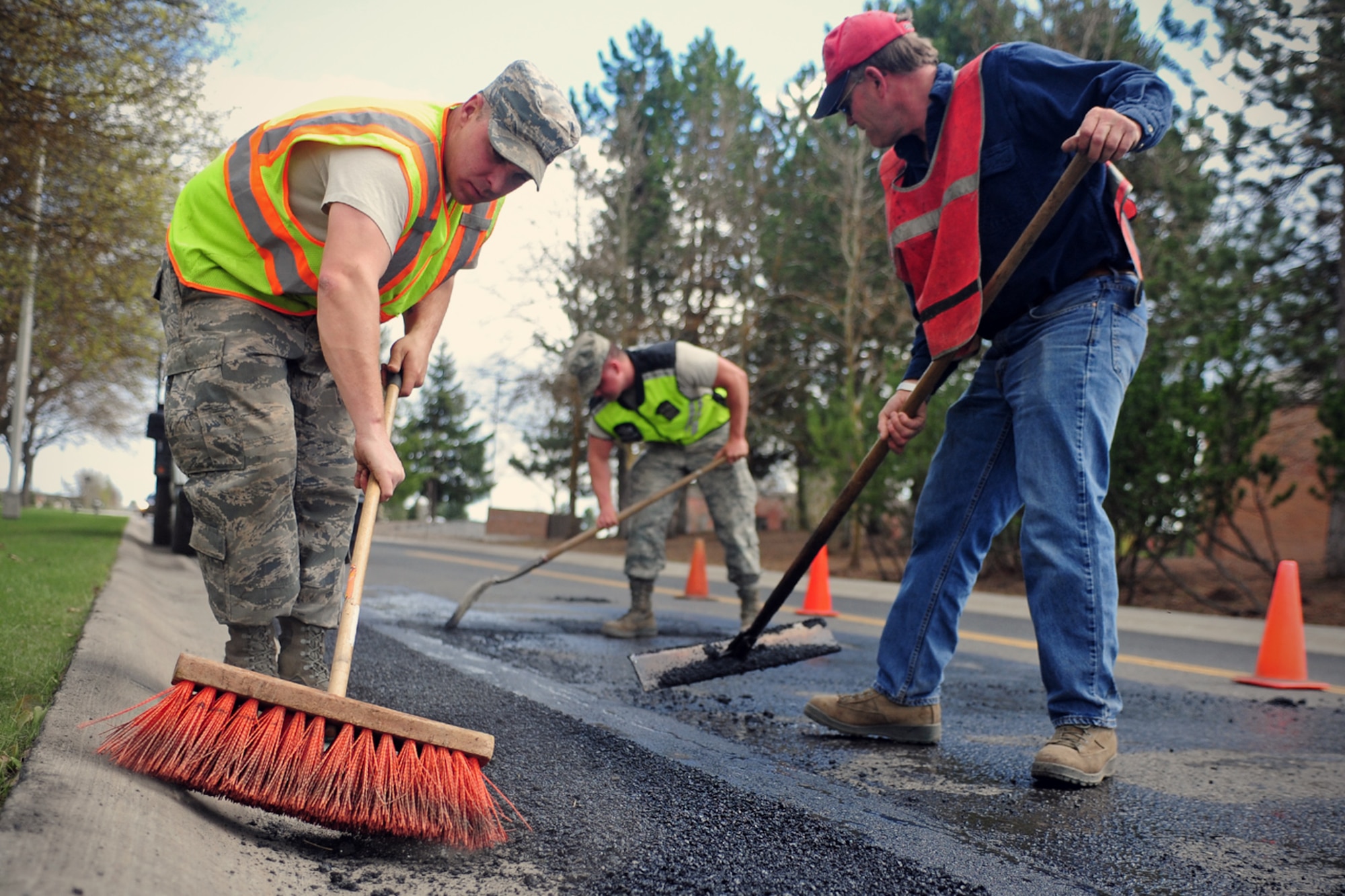Pavement and equipment operators with the 92nd Civil Engineer Squadron lay hot asphalt over holes on the road for repair at Fairchild Air Force Base, Wash., April 28, 2014. (U.S. Air Force photo by Senior Airman Taylor Curry/Released)