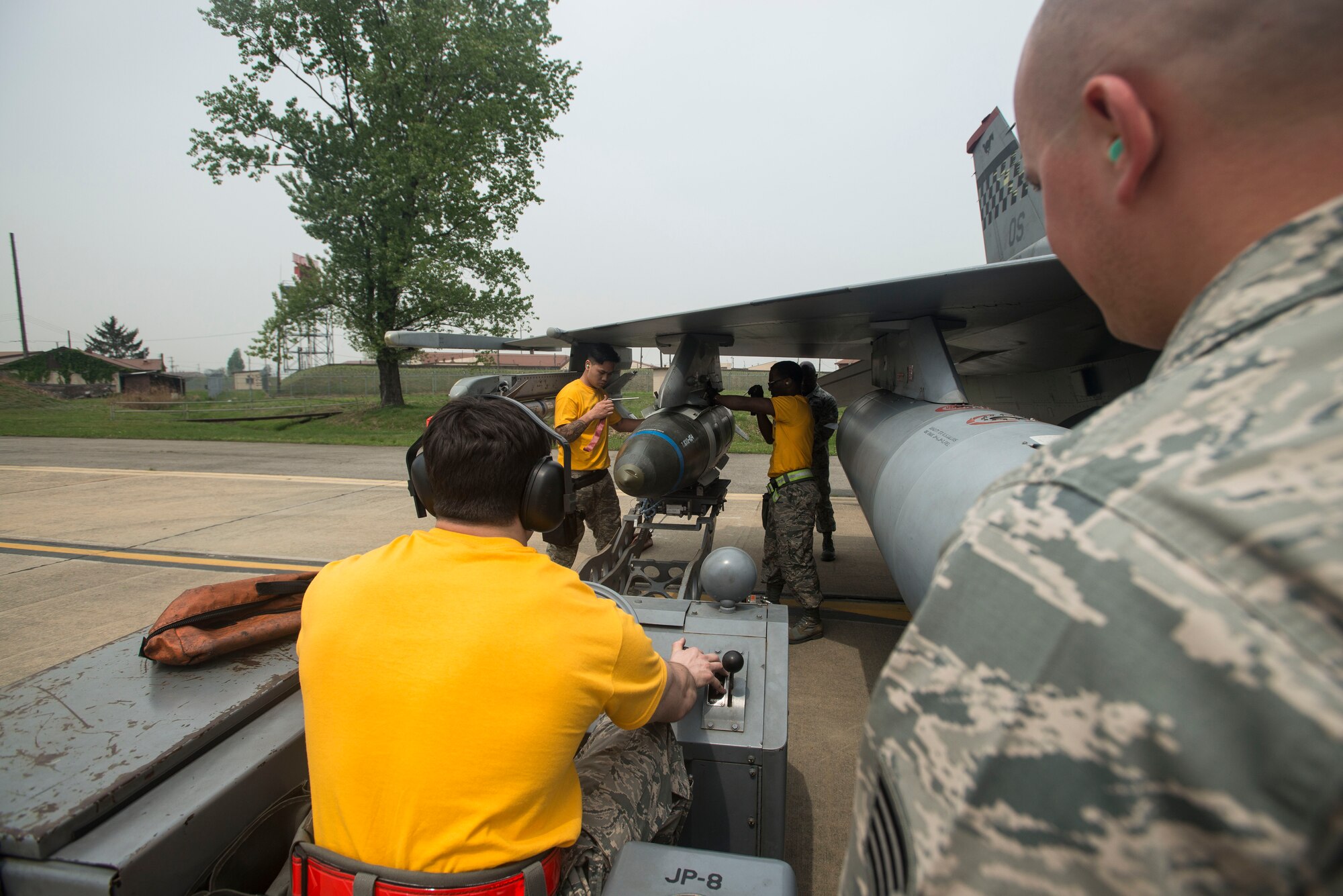 The 80th Aircraft Maintenance Unit weapons loading crew from Kunsan Air Base, Republic of Korea, guide a missle onto an F-16 during the 2014 Korean Peninsula Weapons Loading Competition April 26, at Osan Air Base. During the competition, teams were evluated on safety, reliability, technical proficienty and the timliness of their performance. (U.S. Air Force photo by Staff Sgt. Jake Barreiro)