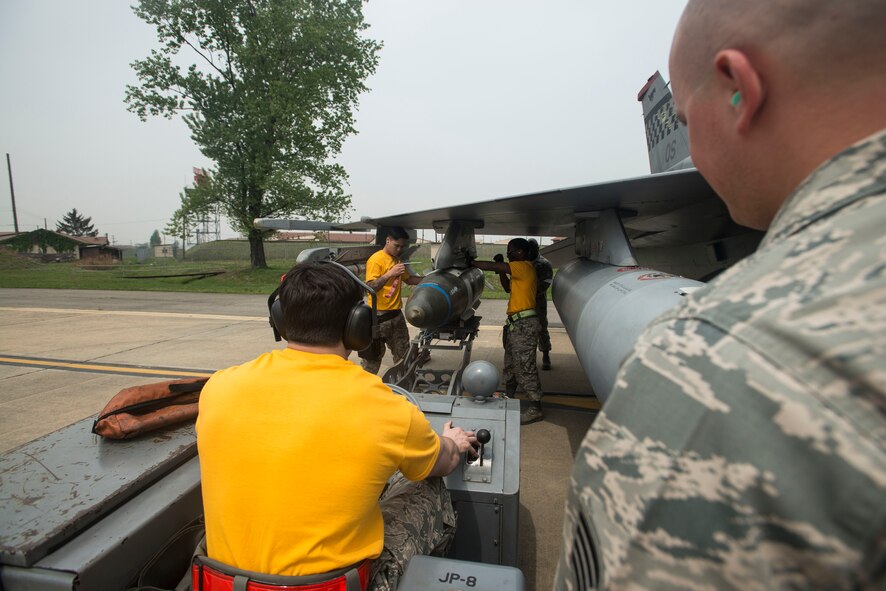 The 80th Aircraft Maintenance Unit weapons loading crew from Kunsan Air Base, Republic of Korea, guide a missle onto an F-16 during the 2014 Korean Peninsula Weapons Loading Competition April 26, at Osan Air Base. During the competition, teams were evluated on safety, reliability, technical proficienty and the timliness of their performance. (U.S. Air Force photo by Staff Sgt. Jake Barreiro)