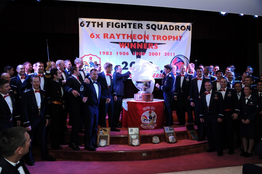 U.S. Air Force Lt. Gen. Jan-Marc Jouas, U.S. Forces, Korea deputy commander and 7th Air Force commander, and Mark Kula, Raytheon Company Tactical Airborne Systems vice president, unveil the Raytheon Trophy during the presentation dinner at the Kadena Officer’s Club on Kadena Air Base, Japan, April 18, 2014. Presented annually since 1953, the Raytheon trophy is awarded to the top air-superiority or air-defense squadron in the Air Force. The 67th Fighter Squadron was named the Raytheon Trophy winner for 2013, and has been awarded the trophy six times. 2013 also marks the third year in a row a fighter squadron stationed at Kadena has won the award. (U.S. Air Force photo by Airman 1st Class Hailey R. Staker)