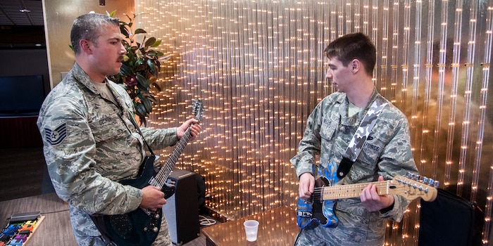 PETERSON AIR FORCE BASE, Colo. -- Airman 1st Class Brett Wells, 21st Communications Squadron (right) and Tech. Sgt. Andrew Decker, 21st Aerospace Medicine Squadron, participate in a guitar duel at The Club April 25. The duel was part of the Wing’s monthly Final Friday event. (U.S. Air Force photo/Craig Denton)