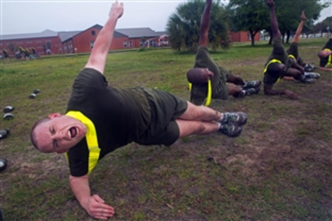 Marine Corps recruit Brenon Sarratori, foreground, strengthens his core muscles during a physical training circuit course on Parris Island, S.C., April 29, 2014. Sarratori is assigned to Kilo Company, 3rd Recruit Training Battalion. Recruits conduct numerous types of strength training to pass the physical and combat fitness tests as well as meet the Marine Corps' physical standards.