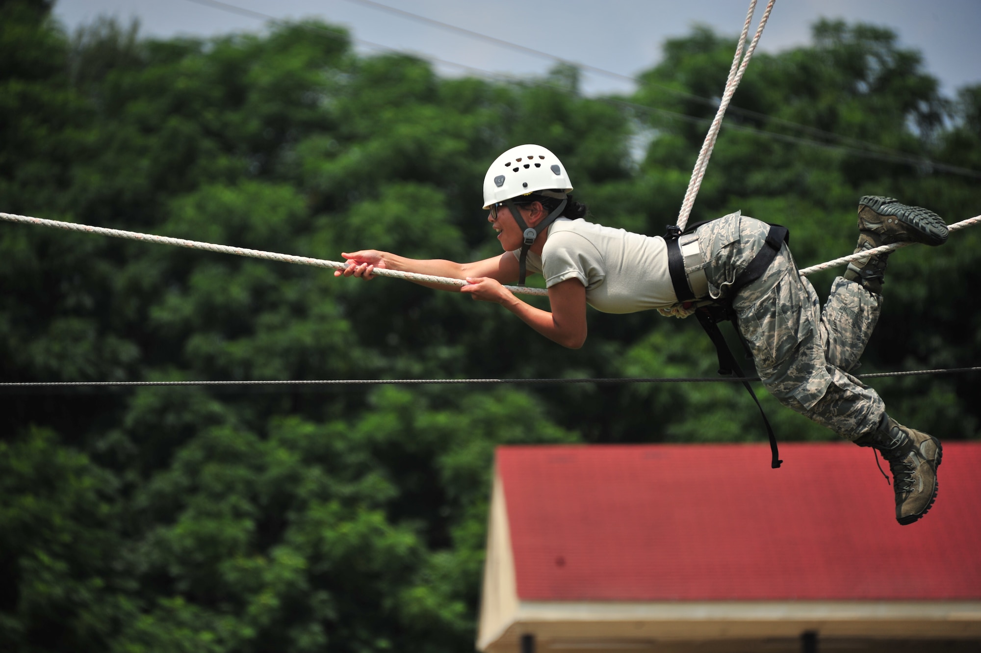 A Commissioned Officer Training School student pulls herself across a rope July 24, 2014, during an exercise conditioning course at Maxwell Air Force Base, Ala. Commissioned medical, legal and chaplain officers must go through COT to receive military leadership training. The ropes course is a confidence and team building part of the training. (U.S. Air Force photo/Staff Sgt. Natasha Stannard)