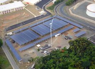 One of two wind turbines on Fort Buchanan stands next to one of its many solar installations. The two wind turbines will produce an estimated 5 percent of the energy consumed by the installation, and a total of 21,824 solar photovoltaic panels will produce about 5.5 megawatts of power, which is at least 60 percent of the installation’s current power demand at its peak production.
 