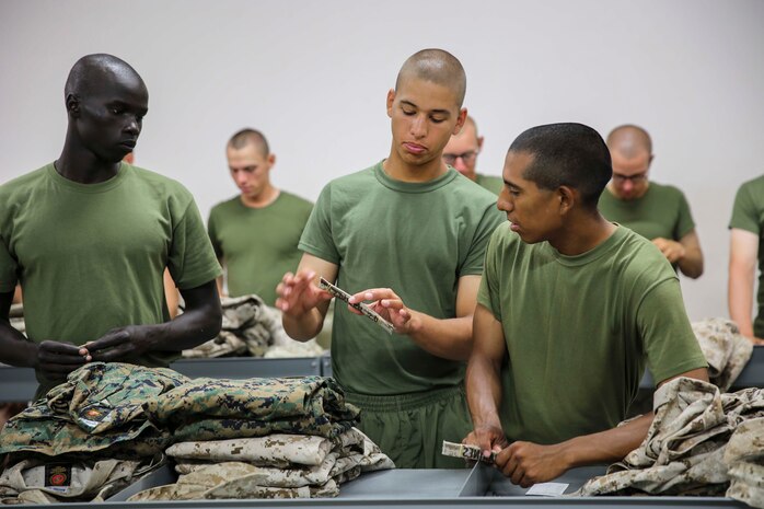 Recruits from Mike Company, 3rd Recruit Training Battalion, look at their name tapes at Marine Corps Recruit Depot San Diego, July 30. The recruits will turn in their camouflag utlities to the tailor tohave their name tapes sewn on them. 