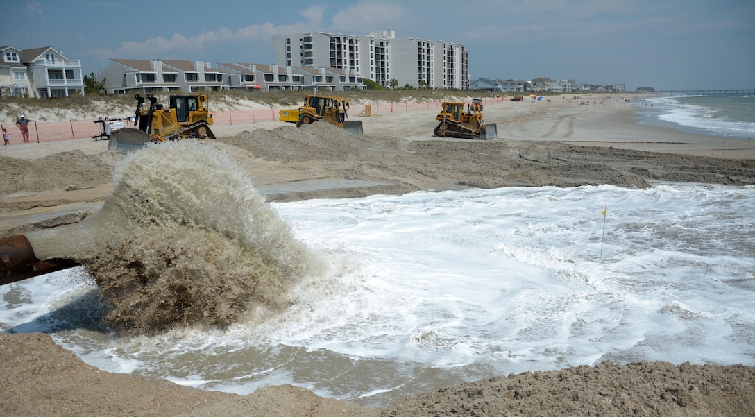 Heavy equipment operators wait until sand stops pumping to begin sculpting it for the proper elevation in the Wrightsville Beach Storm Damage Reduction Project. (USACE photo by Hank Heusinkveld) 