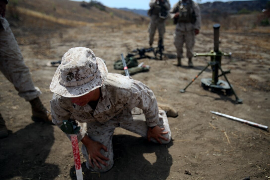 Lance Cpl. Andrew Crotts, a section leader with Company L, 3rd Battalion, 1st Marine Regiment, directs the placement of aiming stakes for his section of mortars aboard Camp Pendleton, Calif., July 29, 2014. The mortars were utilized in support of a live-fire range involving adjacent infantry and machine gun units.