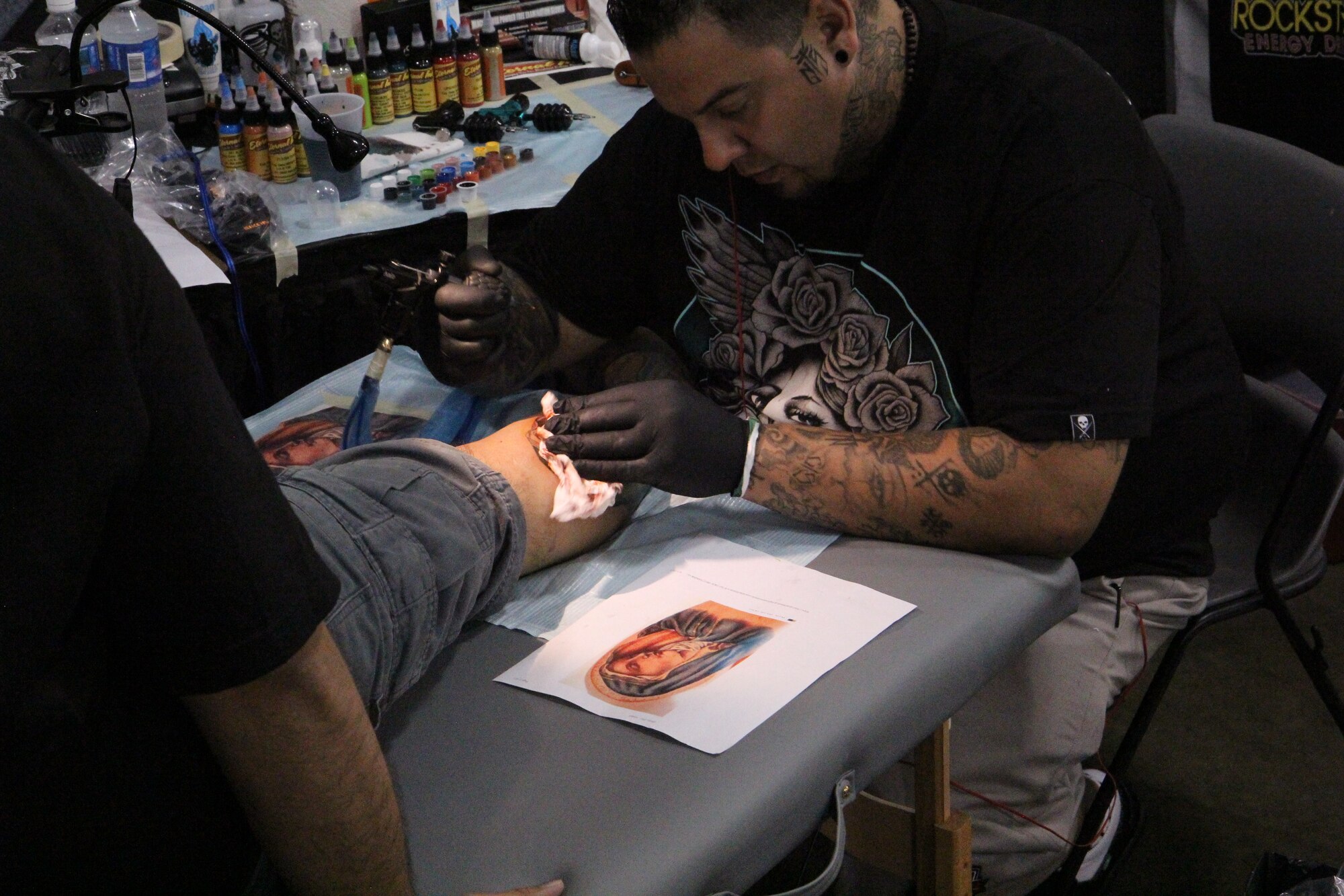 A tattoo artist uses a picture of the Madonna to reference while he works on a tattoo at the Pacific Ink & Art Expo, Blaisdell Exhibition Hall, Honolulu, Hawaii, Aug. 3, 2013. According to Air Force Instruction 36-2903, only tattoos that advocate religious discrimination are prohibited. (U.S. Air Force photo by Tech. Sgt. Phyllis Keith)
