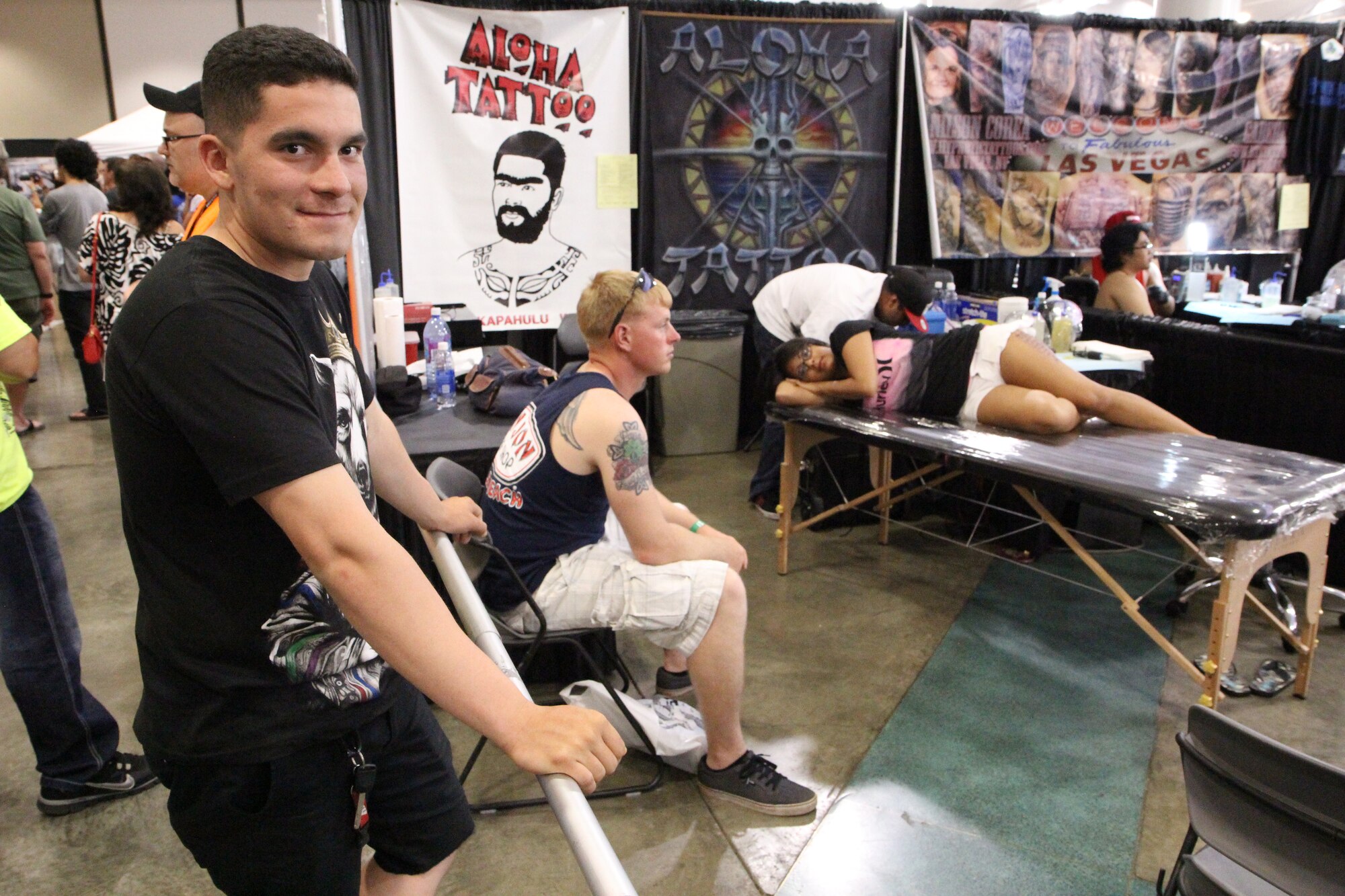 From left, an Army soldier looks at the camera while his battle buddy waits his turn to get a tattoo at the Pacific Ink & Art Expo, Blaisdell Exhibition Hall, Honolulu, Hawaii, Aug. 4, 2013. In March 2013, the U.S. Army revised their regulation restricting the number of visible tattoos a soldier can have below the elbows or knees to no more than four. (U.S. Air Force photo by Tech. Sgt. Phyllis Keith)