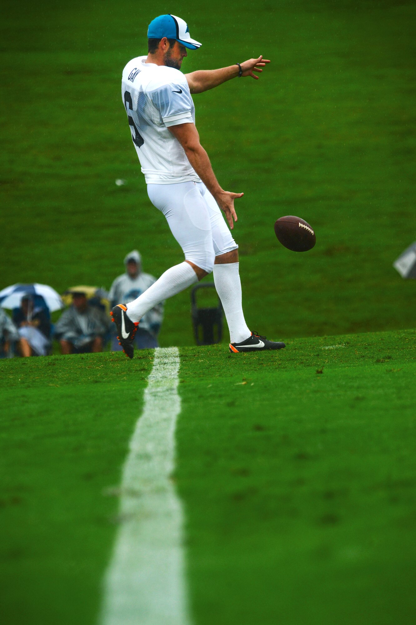 A Carolina Panthers football player drops a football in preparation for a kick during training camp in Spartanburg, S.C., July 31, 2014. During the five-hour practice, Team Shaw members watched the team run drills and practice for their upcoming season. (U.S. Air Force photo by Airman 1st Class Jensen Stidham/Released)