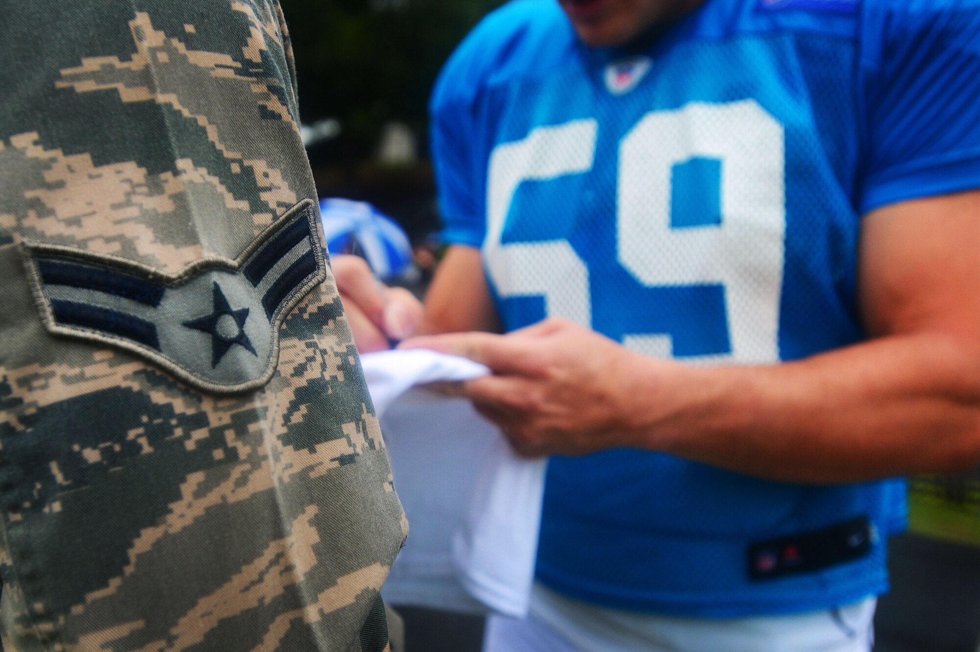 A U.S. Air Force Airman receives an autograph from a Carolina Panthers football player in Spartanburg, S.C., July 31, 2014. While visiting the training camp, Team Shaw members had Panthers memorabilia signed by several players after watching the team practice. (U.S. Air Force photo by Airman 1st Class Jensen Stidham/Released)
