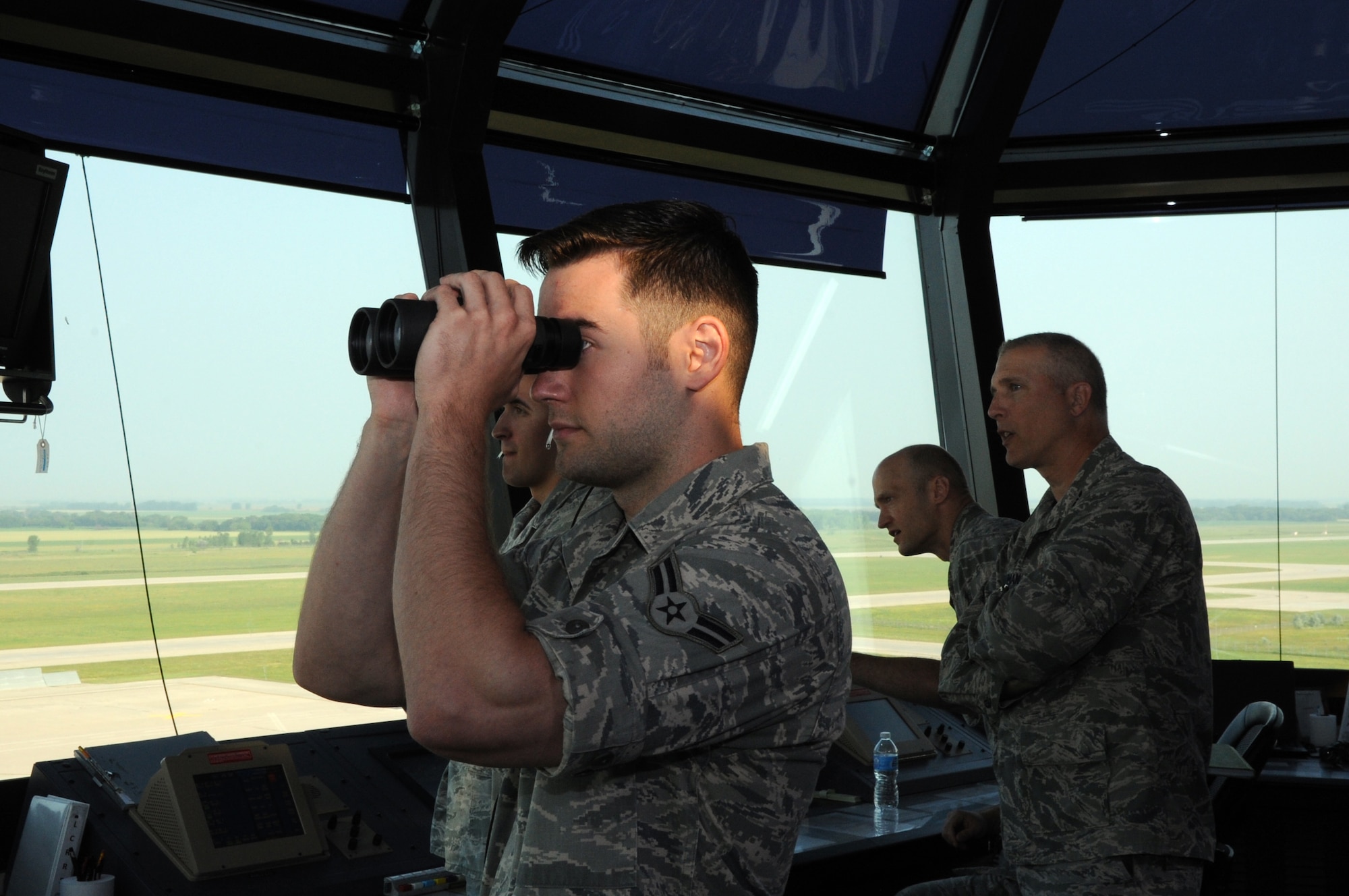 Airman 1st Class Cole Nesbitt (holding binoculars), 319th Operations Support Squadron air traffic control journeyman, and Senior Airman Kyle Thwing, 319th OSS air traffic controller, monitor aircraft maneuvers in the air traffic control tower on Grand Forks Air Force Base, N.D., August 1, 2014. Joining him in the tower are Col. Paul Bauman (far right), 319th Air Base Wing commander, and Col. Robert Cook (second from right), 319th ABW vice commander. They are watching the takeoff of an RQ-1 Predator that heralded the first flight of unmanned aircraft in unrestricted airspace. (U.S. Air Force photo/Staff Sgt. David Dobrydney)