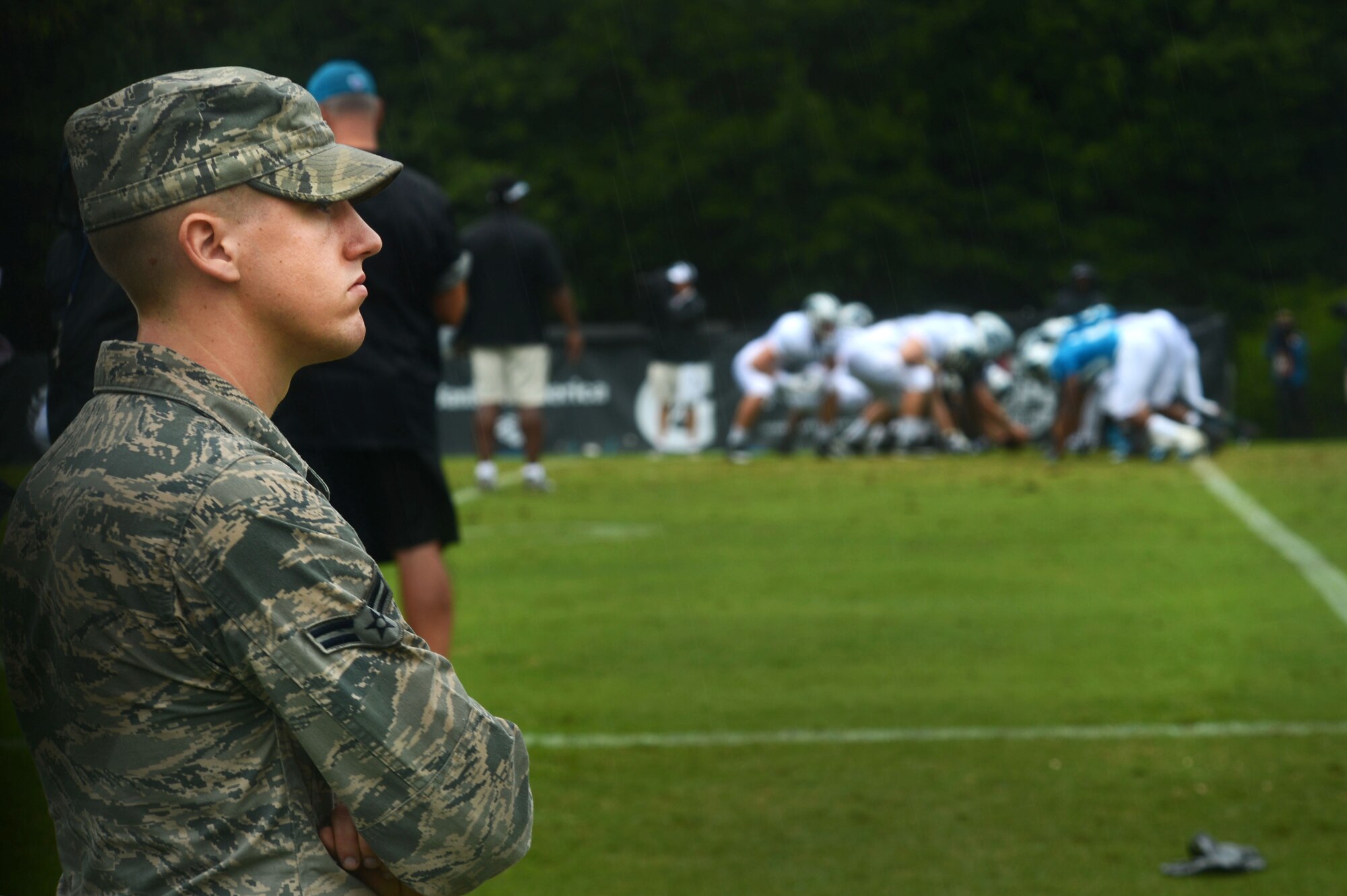 U.S. Air Force Airman 1st Class Aaron Shive, 20th Aircraft Maintenance Squadron weapons apprentice, watches a Carolina Panthers football practice in Spartanburg, S.C., July 31, 2014. During their visit, five Team Shaw members spent several hours watching the team run various drills. (U.S. Air Force photo by Airman 1st Class Jensen Stidham/Released)