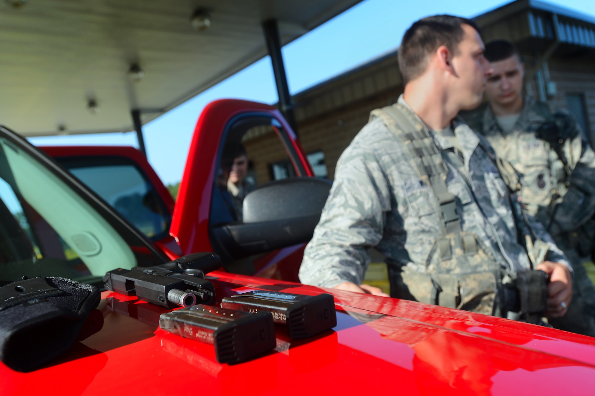 Two magazines of 9mm ammunition and a handgun sit on the hood of a truck at Shaw Air Force Base, S.C., July 24, 2014. A routine vehicle inspection revealed the handgun and magazines in a commercial vehicle. (U.S. Air Force photo by Airman 1st Class Jensen Stidham/Released)