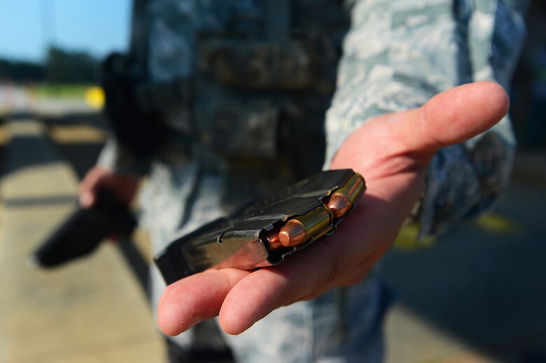 A 20th Security Forces Squadron installation entry control Airman holds two magazines of 9mm rounds at Shaw Air Force Base, S.C., July 24, 2014. Security forces defenders found the magazines and handgun, unintentionally brought to base by a civilian contractor, during a routine check at the commercial vehicle inspection area. (U.S. Air Force photo by Airman 1st Class Jensen Stidham/Released)