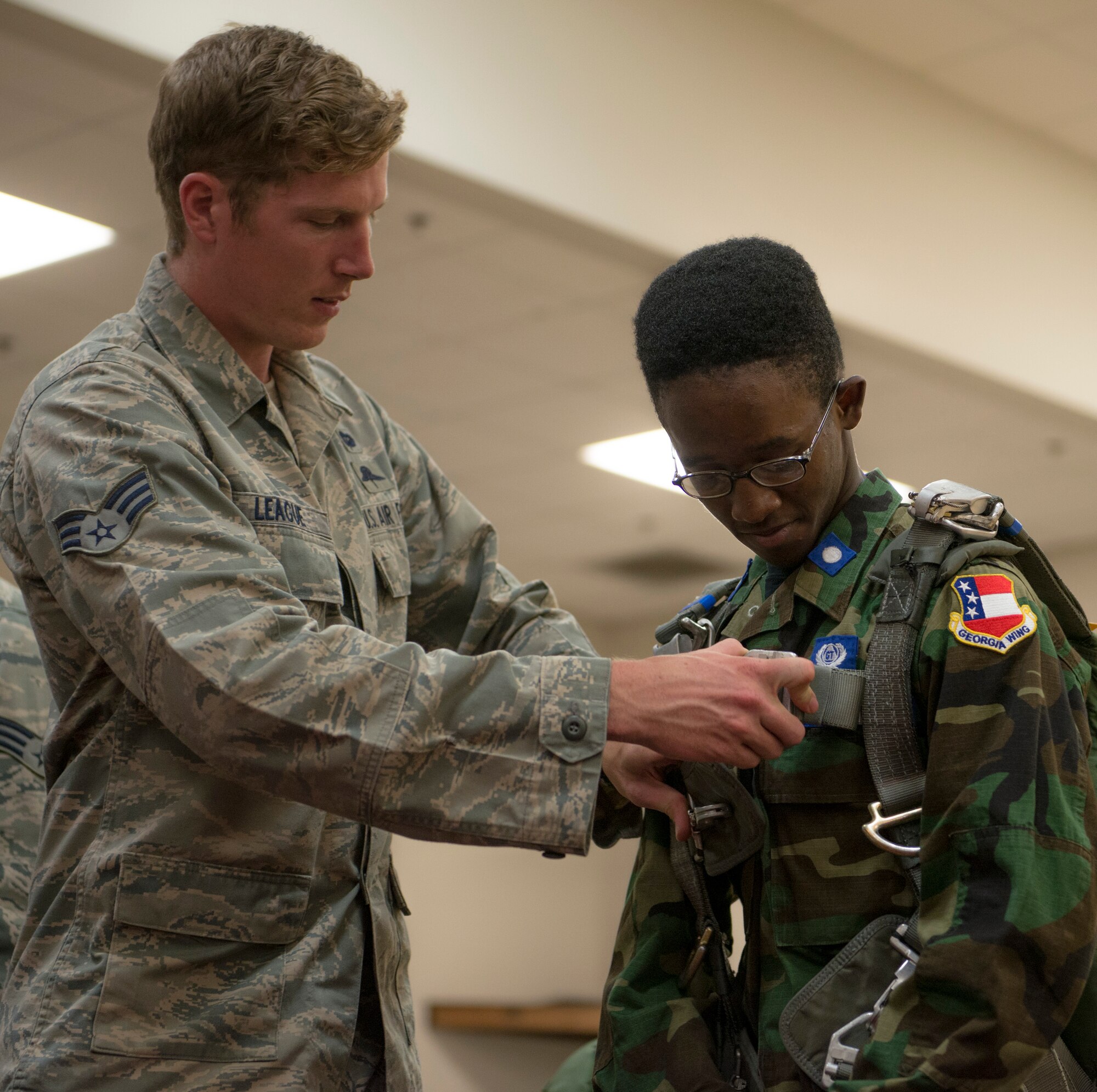 U.S. Air Force Senior Airman Tristan League, 38th Rescue Squadron pararescueman, demonstrates to Anthony Amir Chase-Hill, Civil Air Patrol Cadet, how to use a parachute bag during a base tour July 31, 2014, at Moody Air Force Base, Ga. Chase-Hill expressed his excitement to see Moody because of his aspiration to become a Combat Rescue Officer. (U.S. Air Force photo by Airman 1st Class Dillian Bamman/Released)