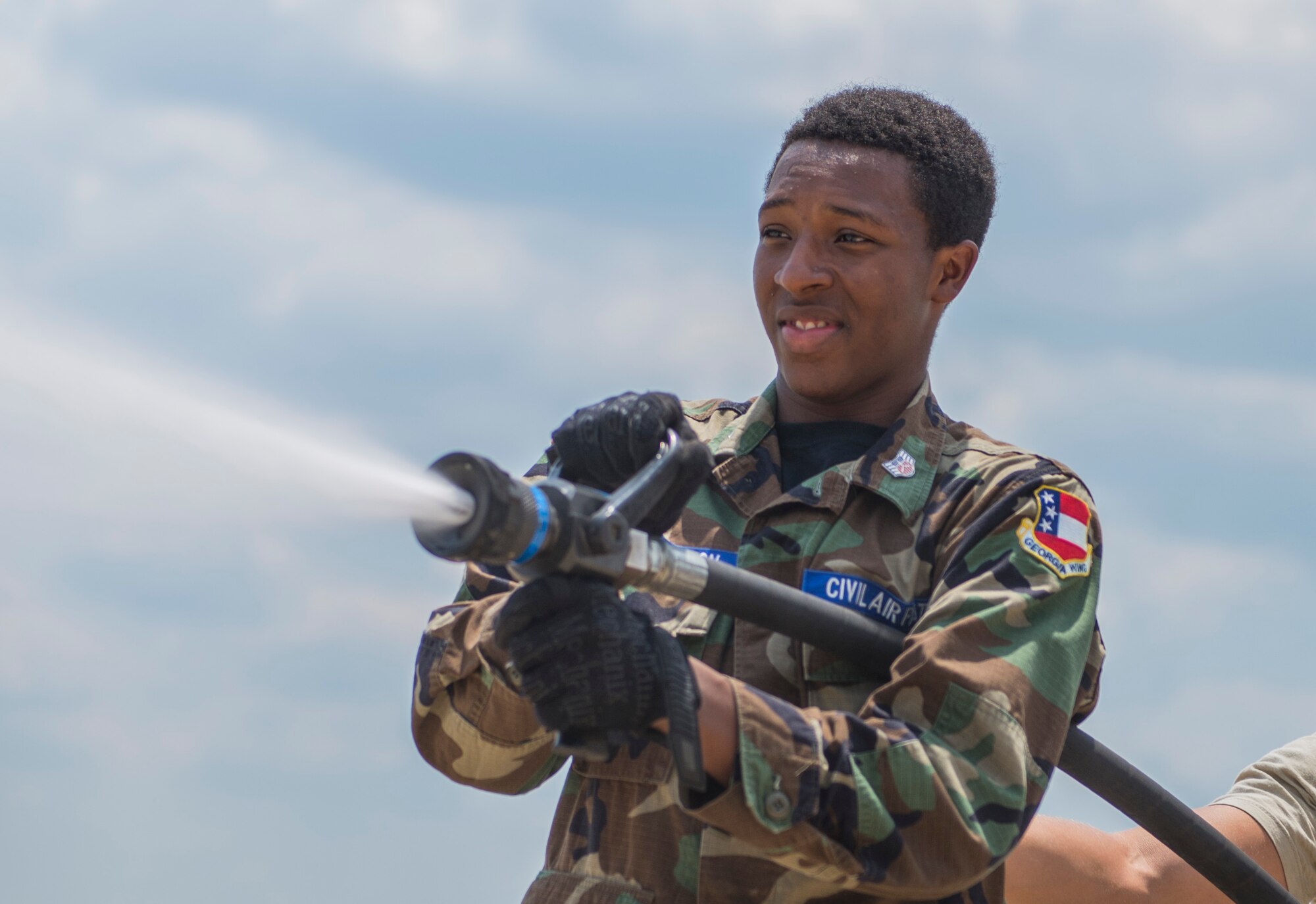 Civil Air Patrol Cadet Zach Hutchinson sprays a high-pressure water hose during a base tour July 31, 2014, at Moody Air Force Base, Ga. The composite squadron from Albany, Ga., visited the base to better understand Moody’s mission. (U.S. Air Force photo by Airman 1st Class Dillian Bamman/Released)