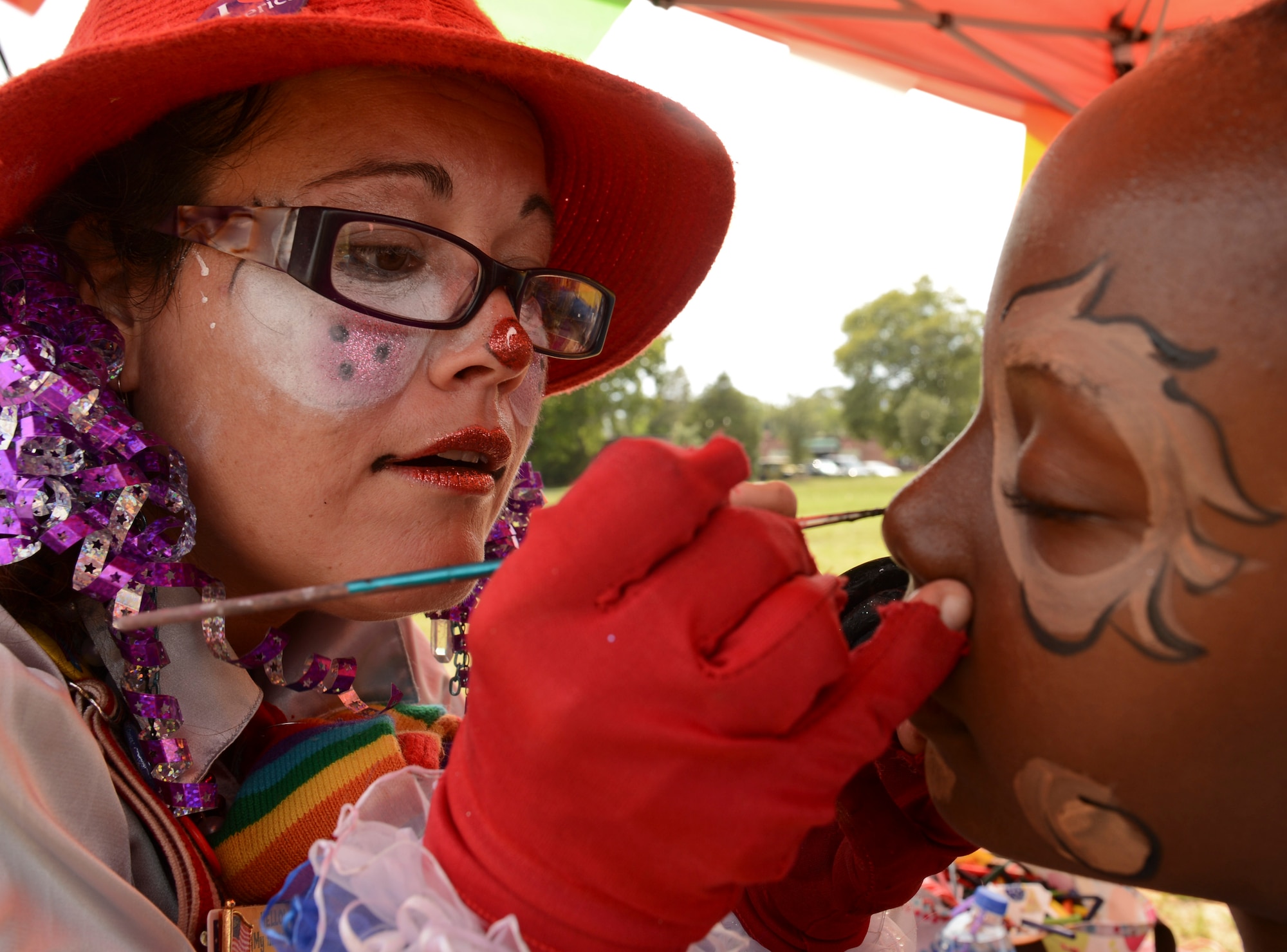 Ms. Trixie the Clown, with Low Country Party Animals, paints Armoni Doctor, daughter of U.S. Army Sgt. Christine Johnson, Army Central supply NCO, during the Kids Jamboree at Shaw Air Force Base, S.C., July 30, 2014. The purpose of the event was to provide a fun learning environment for the children on base. (U.S. Air Force photo by Senior Airman Tabatha Zarrella/Released)