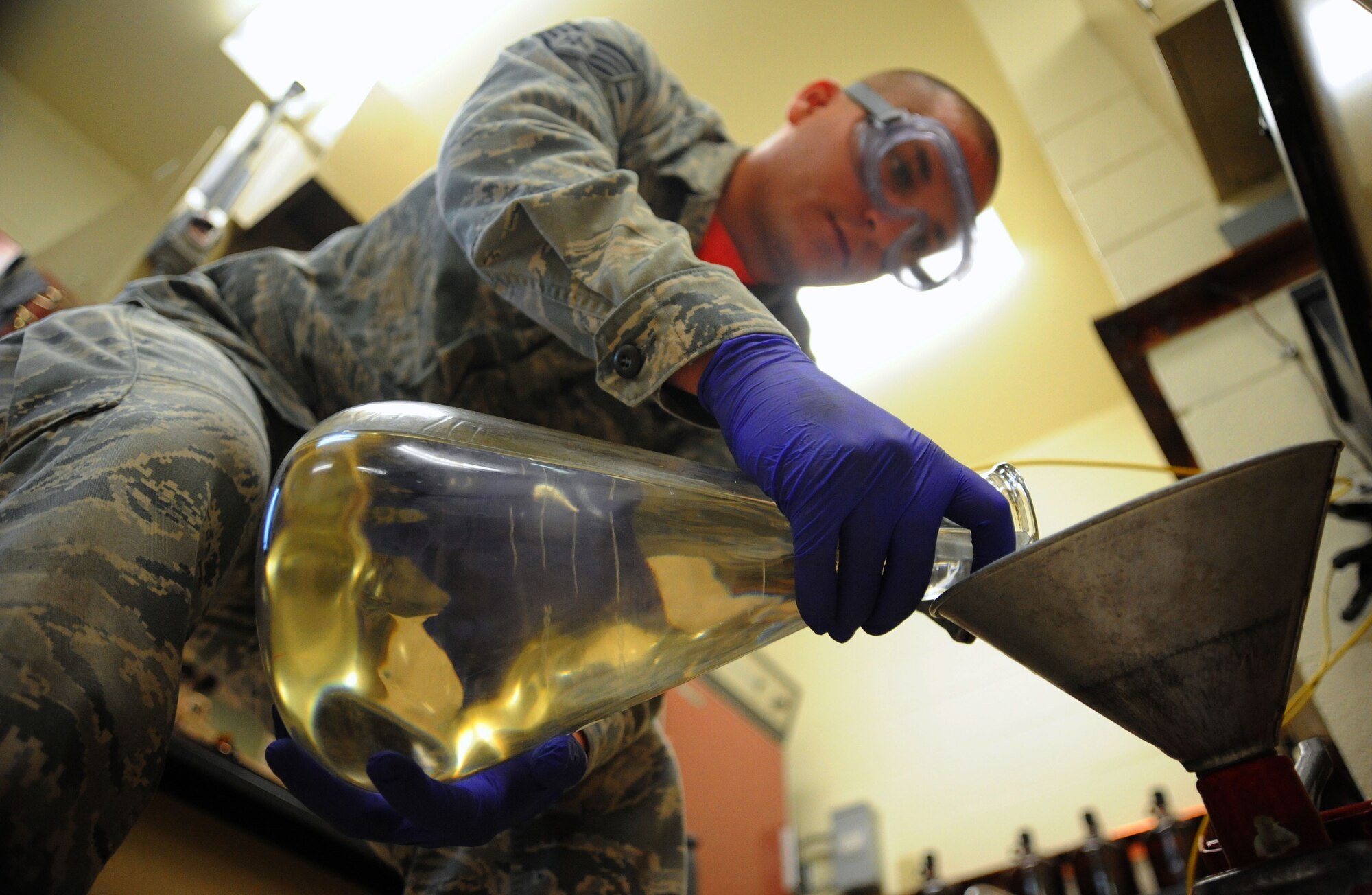 U.S. Air Force Staff Sgt. Andrew Mitalski, 20th Logistics Readiness Squadron fuels laboratory supervisor, pours jet fuel into a container at Shaw Air Force Base, S.C., August 1, 2014. The lab could test anywhere from five to 20 samples a week with each sample requiring six tests. (U.S. Air Force photo by Airman 1st Class Michael Cossaboom/Released)