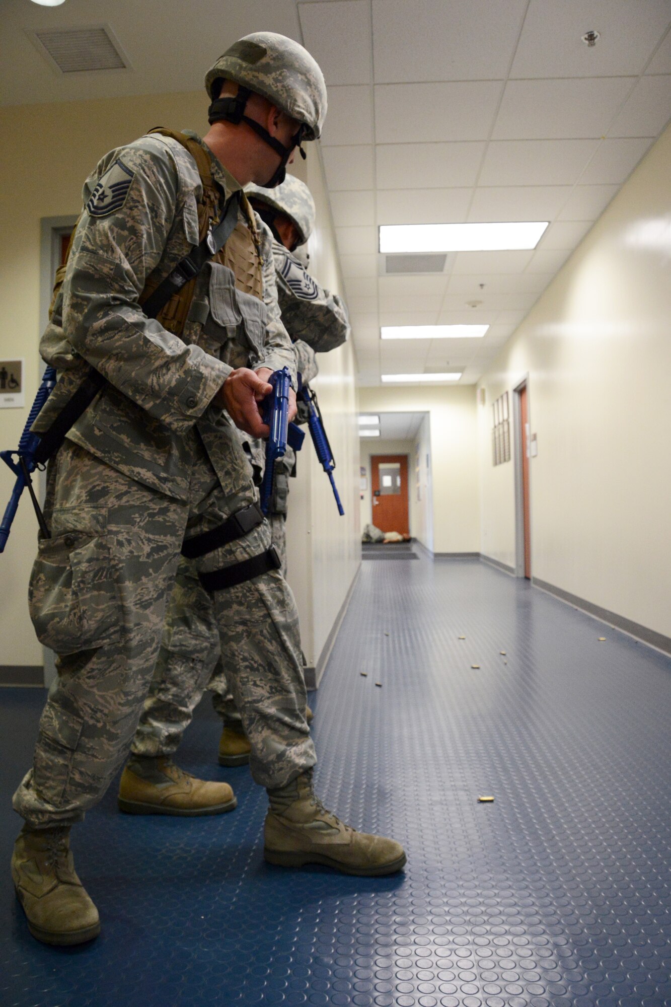 Master Sgt. Christopher Redo, Senior Master Sgt. Kurt Smith and Master Sgt. Richard Marks (not shown) assess the tactical situation down a long hallway after neutralizing a simulated active shooter during a training exercise at Bradley Air National Guard Base, East Granby, Conn. on July 30, 2014. All three of the security forces first responders are in the process of clearing the building ensuring there are no more simulated threats to the base. In the distance, an exercise participant is playing the part of a victim with a simulated gunshot wound, yelling for medical assistance to add a layer of realism to the scenario. (U.S. Air National Guard photo by Tech. Sgt. Joshua Mead/Released)