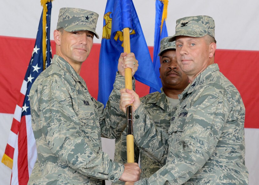 Brig. Gen. Scott Pleus, 56th Fighter Wing commander, passes the guidon to Col. James Kossler, 56th Mission Support Group commander, during a change-of-command ceremony July 24 in Hanger 431 at Luke Air Force Base. (U.S. Air Force photo/Senior Airman Devante Williams)