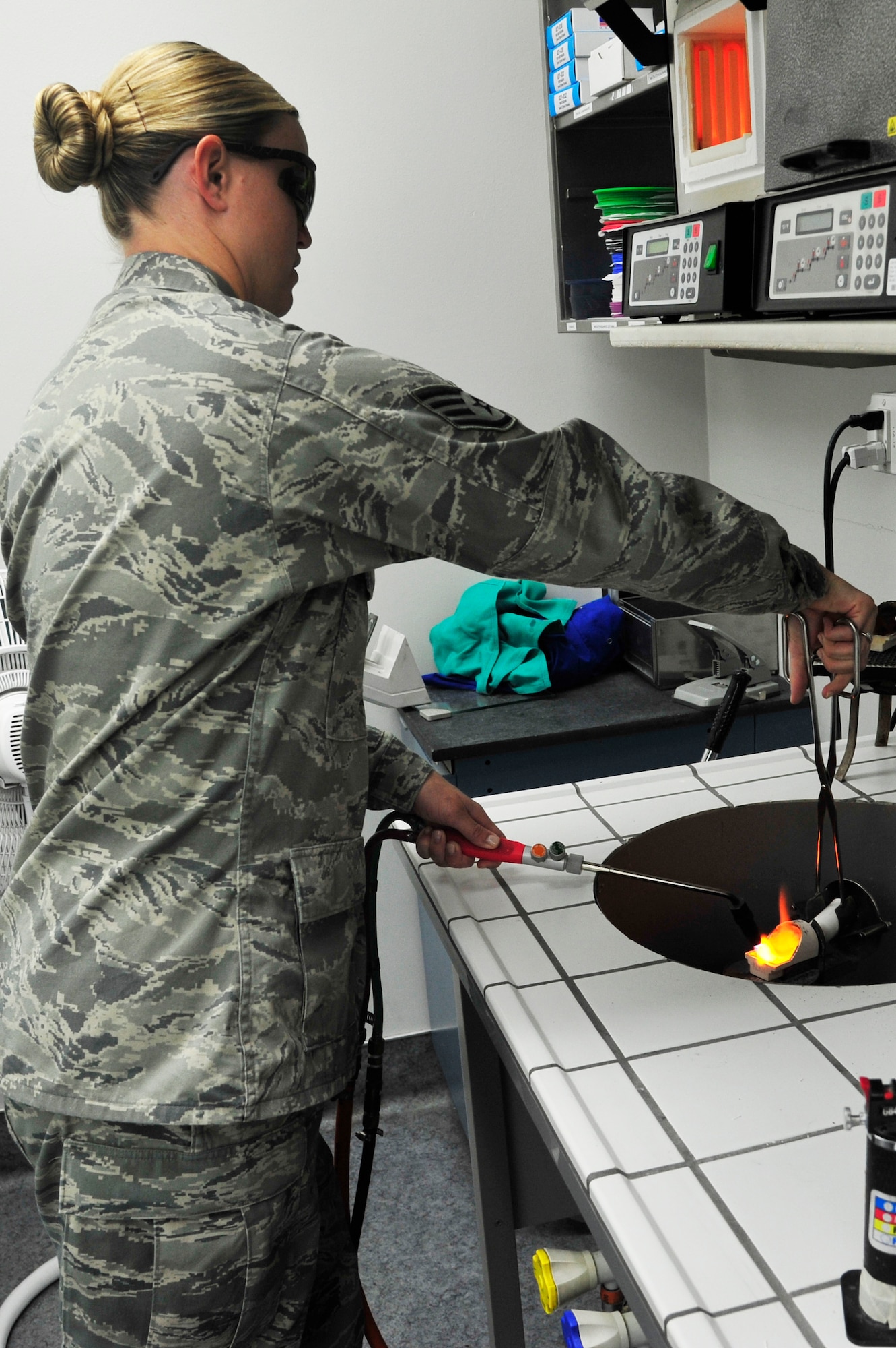 Staff Sgt. Maddie Baker, 56th Dental Squadron Dental Laboratory technician, torches a crucible in the casting well. Gold is put into the crucible, melted and cast into an investment ring, which is an inverted mold of the tooth. (U.S. Air Force photo/Senior Airman Grace Lee)