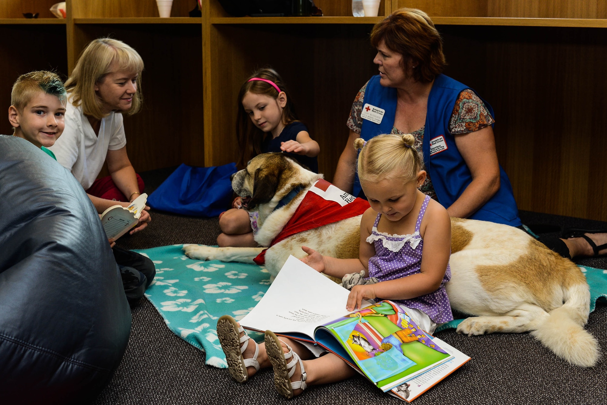 Children meet with Rocky, a Red Cross Morale Dog, in the library at Spangdahlem Air Base, Germany, July 31, 2014. The Red Cross dogs help the Chaplain Corps by meeting with people who suffer from traumatic events or feel stressed. The Red Cross Dogs Aim to reduce stress and increase morale in the community. (U.S. Air Force photo by Airman 1st Class Kyle Gese/Released)