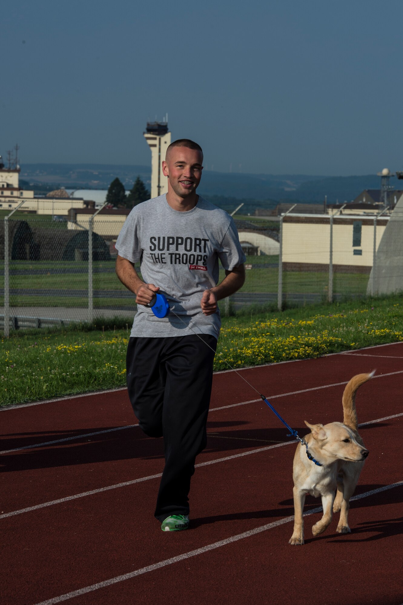 U.S. Air Force Senior Airman Michael Duarte, 52nd Operations Support Squadron air traffic controller from Bend, Ore., and his dog Mauro participate in the Relay For Life event on the base track at Spangdahlem Air Base, Germany, Aug. 1, 2014. The event raised awareness of base and national support groups dedicated to helping cancer survivors and their families. (U.S. Air Force photo by Staff Sgt. Christopher Ruano/Released)