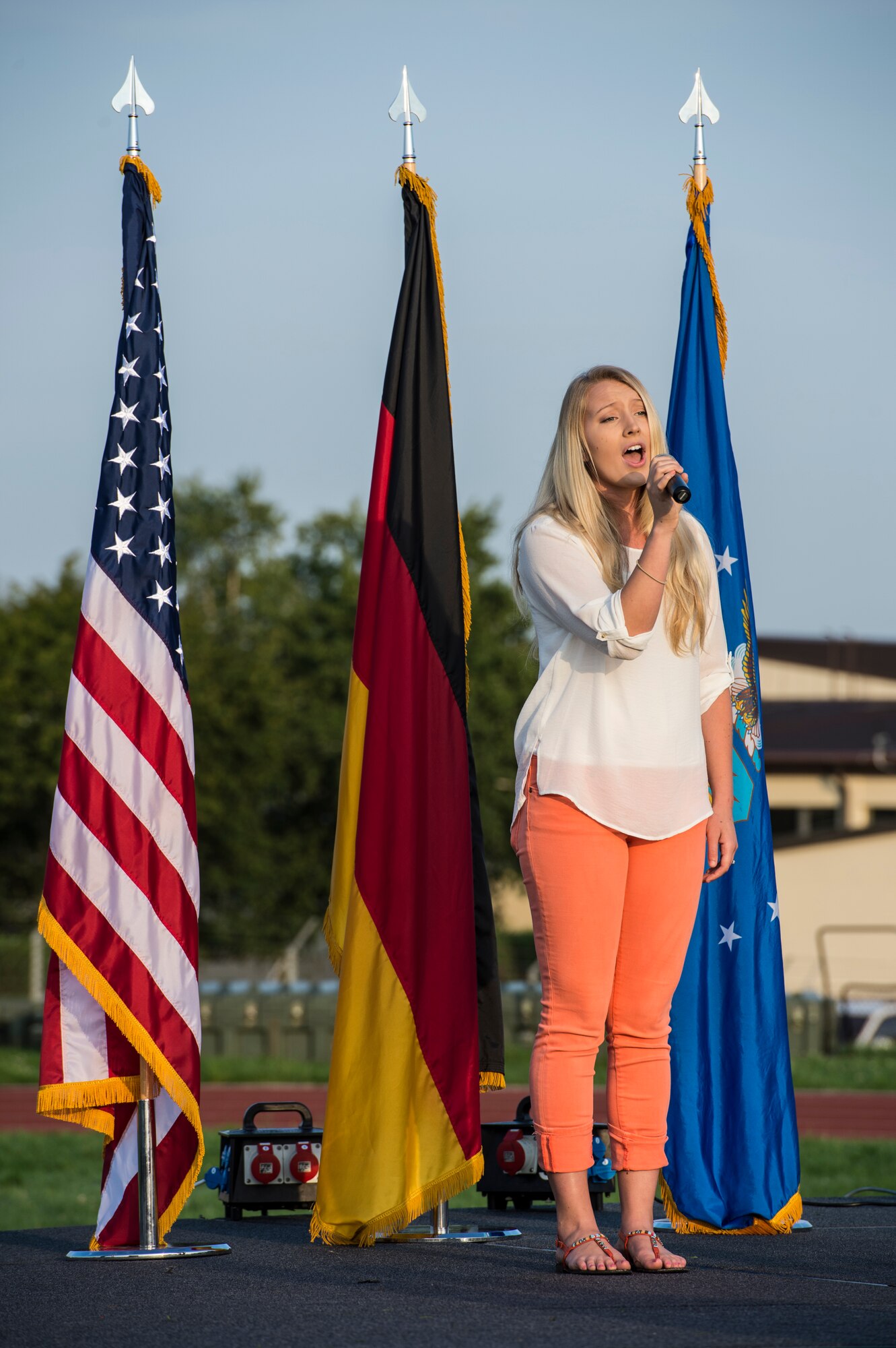 Alexandra Duarte, Vacaville, Calif., native and wife of U.S. Air Force Senior Airman Michael Duarte, 52nd Operations Support Squadron air traffic controller from Bend, Ore., sings the U.S. national anthem during the opening ceremony of Relay For Life event at Spangdahlem Air Base, Germany, Aug. 1, 2014. The opening ceremony also included speeches from U.S. Air Force Col. Peter Bilodeau, 52nd Fighter Wing commander, and cancer survivor Amanda Atwell, wife of U.S. Air Force Maj. Richard Atwell, 52nd Comptroller Squadron commander. (U.S. Air Force photo by Staff Sgt. Christopher Ruano/Released)