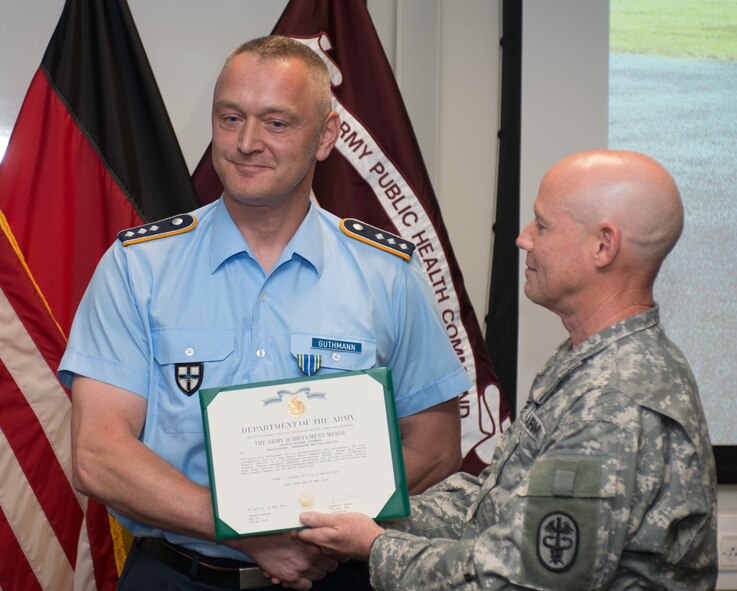 Col. James W. Boles (right), U.S. Army Public Health Command Region-Europe, presents an Army Achievement Medal to Capt. Michael Guthmann, from the German air force Center of Aerospace Medicine, during an award ceremony July 23, 2014, in Landstuhl Regional medical Center, Germany. Guthamann received the medal for leading an obstacle course for U.S. Soldiers, Airmen and Sailors that consisted of firing German rifles and pistols, track and field, a ruck march and much more. (U.S. Air Force photo/Senior Airman Jonathan Stefanko)