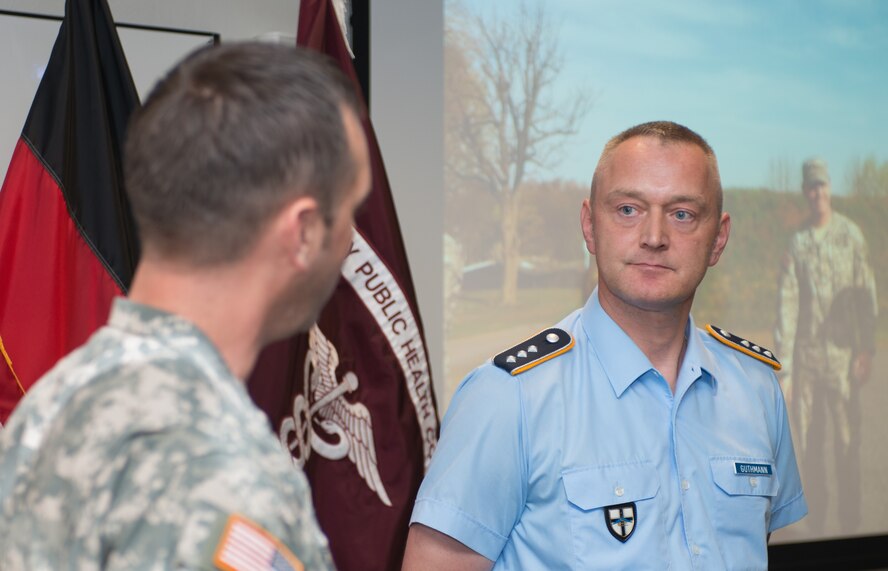 Maj. Michael McCown (left), Public Health Command Region-Europe, chief of operations, talks about the accomplishments of Capt. Michael Guthmann, from the German air force Center of Aerospace Medicine, during an Army Achievement Medal award ceremony  July 23, 2014, in Landstuhl Regional medical Center, Germany. Guthamann received the medal for leading an obstacle course for U.S. Soldiers, Airmen and Sailors that consisted of firing German rifles and pistols, track and field, a ruck march and much more. (U.S. Air Force photo/Senior Airman Jonathan Stefanko)