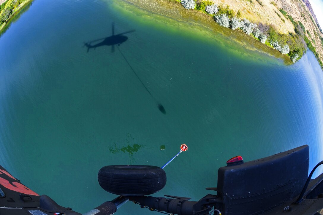 Army pilots maneuver their UH-60 Black Hawk helicopter to pick up water to fight wildfires near the Chiwaukum Creek and Carlton Complex fires near Leavenworth, Wash., July 31, 2014.