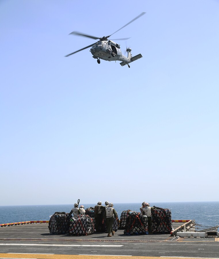 U.S. 5TH FLEET AREA OF RESPONSIBILITY (July 28, 2014) Combat Cargo Marines aboard the amphibious assault ship USS Bataan (LHD 5) hurry to unhook ropes from supply crates during a replenishment at sea. The Bataan is the flagship for the Bataan Amphibious Ready Group and, with the embarked 22nd Marine Expeditionary Unit, is deployed in support of maritime security operations and theater security cooperation efforts in the U.S. 5th Fleet area of responsibility. (U.S. Marine Corps photo by Cpl. Caleb McDonald/Released)