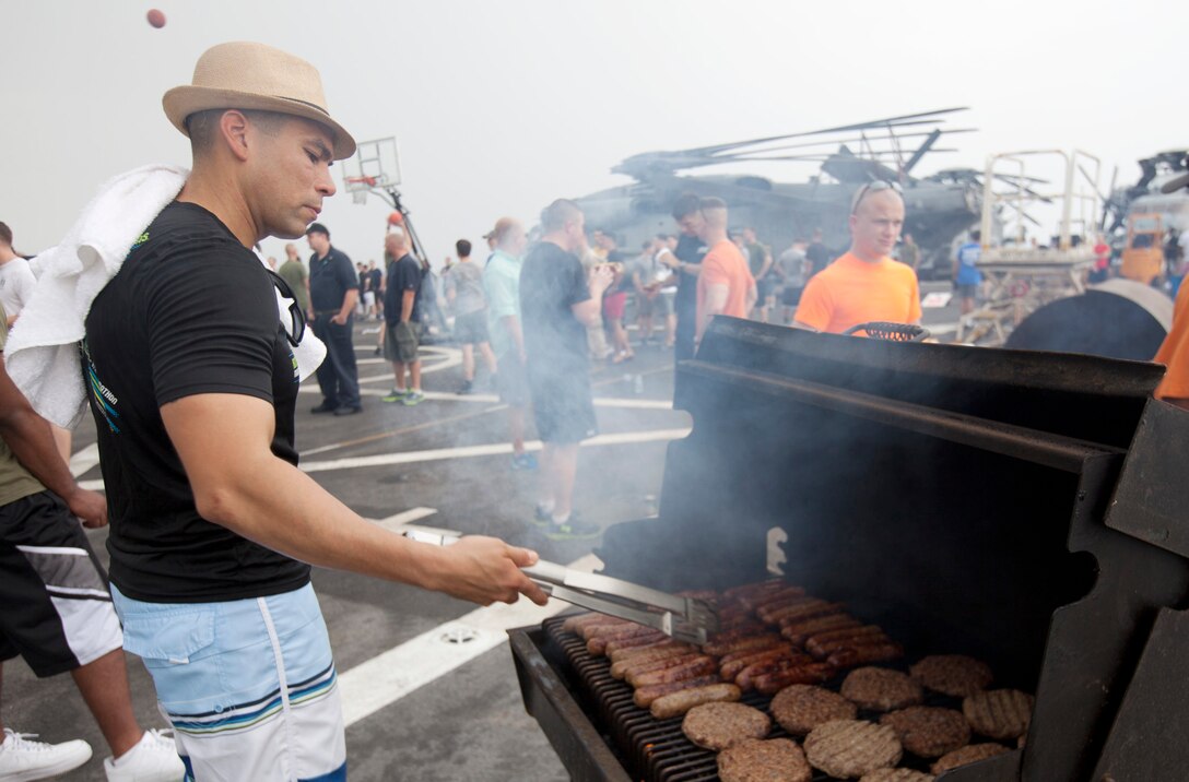 U.S. 5TH FLEET AREA OF RESPONSIBILITY (July 27, 2014) U.S. Marine Corps Gunnery Sgt. Jose Vasquez, Battalion Landing Team 1st Battalion, 6th Marine Regiment, 22nd Marine Expeditionary Unit (MEU), company gunnery sergeant and native of Brooklyn, N.Y., cooks hamburgers and hot dogs during a steel beach picnic hosted by the Marines aboard the amphibious transport dock ship USS Mesa Verde (LPD 19). The 22nd MEU is deployed with the Bataan Amphibious Ready Group as a theater reserve and crisis response force throughout U.S. Central Command and the U.S. 5th Fleet area of responsibility. (U.S. Marine Corps photo by Staff Sgt. Lukas Atwell/Released)