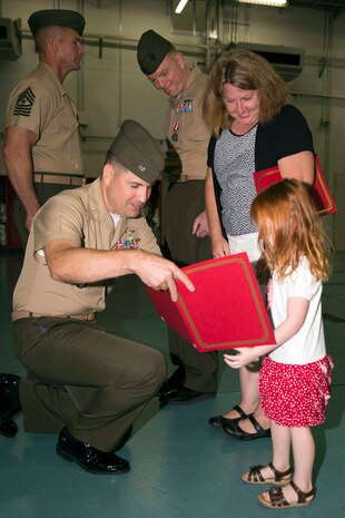 Col. Robert Boucher, station commanding officer, presents Shelby Walker, daughter of Lt. Col. James Walker the station airfield operations officer, with a certificate of appreciation during Walker’s retirement ceremony July 25, 2014, aboard Marine Corps Air Station Iwakuni, Japan. Walker retired after 27 years of service in the Marine Corps.