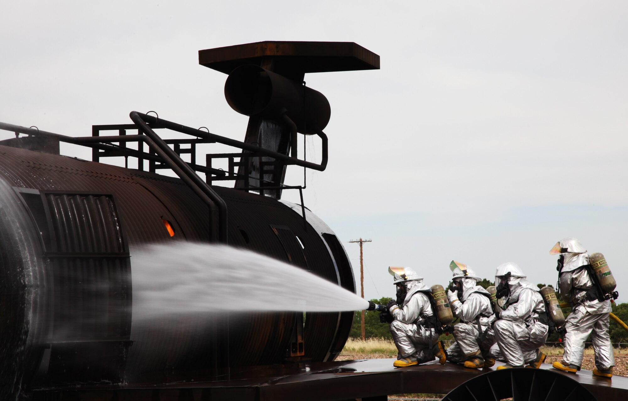 940th Fire Emergency Services Flight reservists make an initial
entry into a live fire trainer, Hill Air Force Base, Utah. The KC-10
Extender mockup uses a controlled propane fire to simulate aircraft
emergencies. Live fire is used so firefighters experience the intensity and
heat of real fire. (U.S. Air Force photo by TSgt. Kenneth McCann/Released) 
