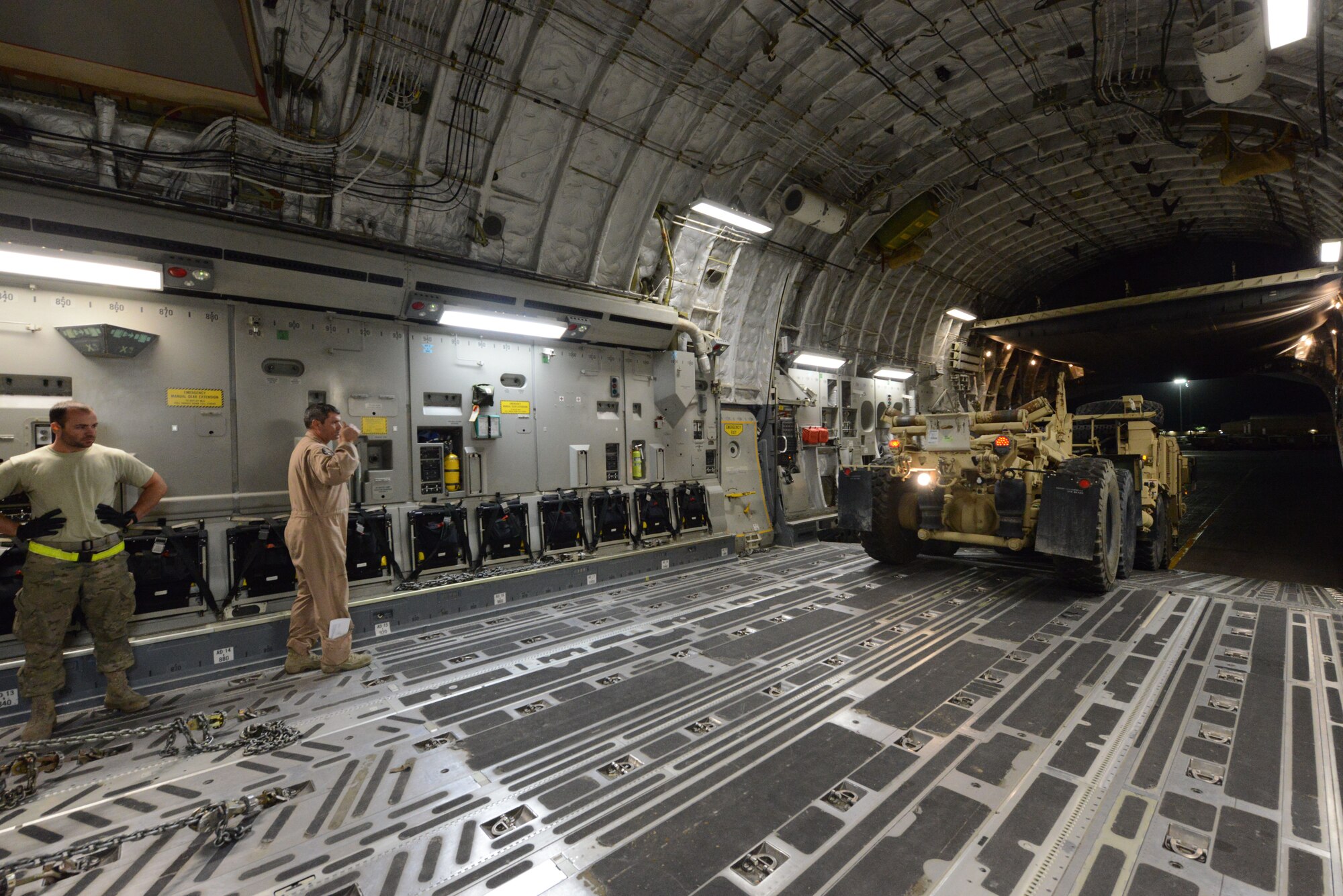 U.S. Air Force Senior Airman Jerry Hullette, a cargo processor assigned to the 455th Expeditionary Aerial Port Squadron, stands by as Master Sgt. John Sadorf, a C-17 Globemaster III loadmaster assigned to the 817th Expeditionary Airlift Squadron, guides the driver of a Heavy Expanded Mobility Tactical Truck onto the aircraft at Bagram Airfield, Afghanistan July 20, 2014. Airmen assigned to the 455 EAPS worked with two 817 EAS loadmasters to off-load six Afghan ambulatory vehicles before uploading two Heavy Expanded Mobility Tactical Trucks within two hours of landing at Bagram. Hullette is a native of Lincolnton, N.C.  and deployed from the 436th Aerial Port Squadron, Dover Air Force Base, Del., and Sadorf is a reservist deployed from the 313th Airlift Squadron, McChord Field, Wash. (U.S. Air Force photo by Master Sgt. Cohen A. Young/Released)