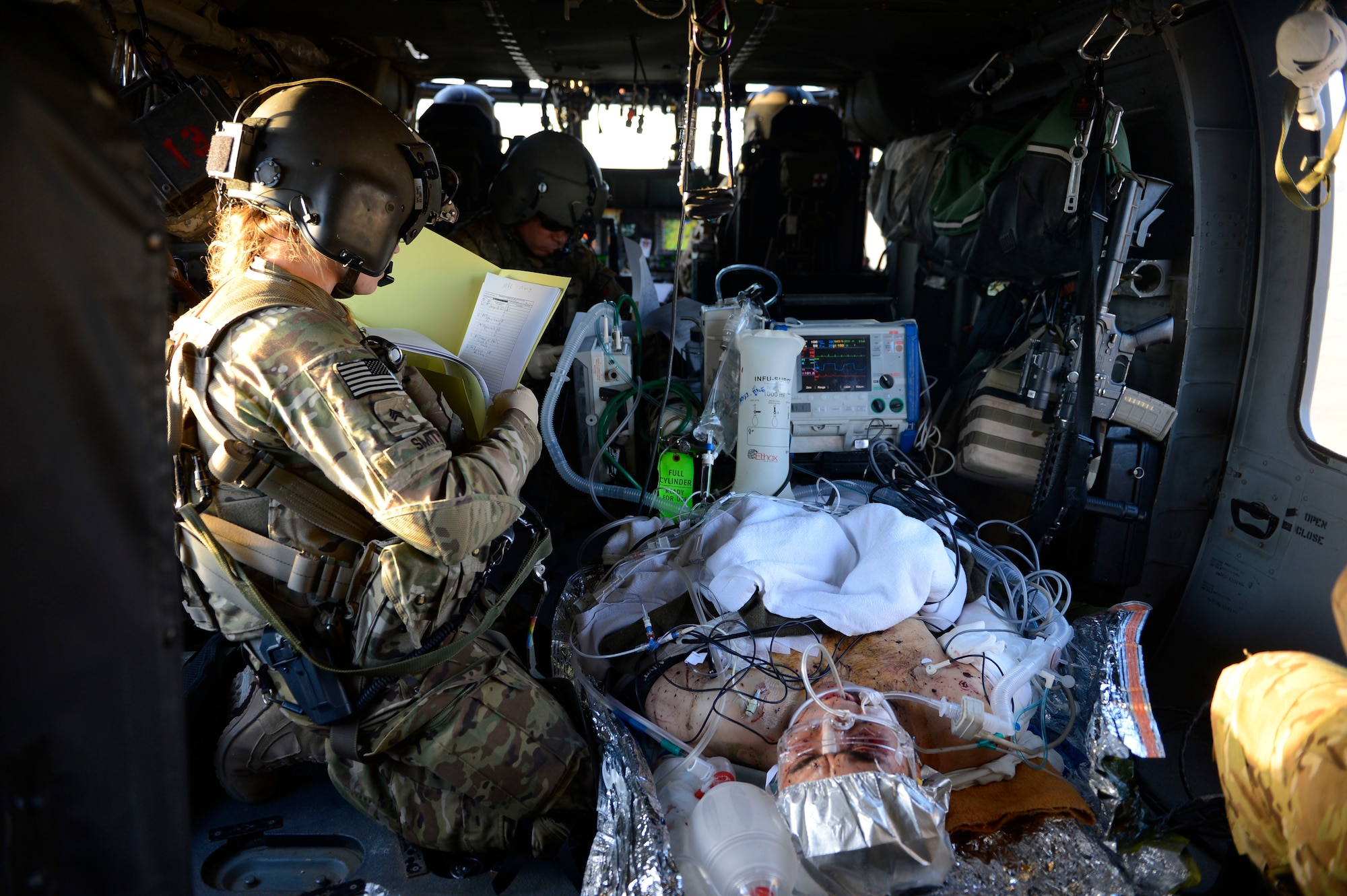 U.S. Army Sgt. Megan Smith, 159th Combat Aviation Brigade medic, reviews a patient's medical records during a patient transfer in Afghanistan, July 2014. Smith is a Devils Lake, North Dakota native deployed from Fort Campbell, Ky. Medevac typically flies with two aircraft and a team of four and may include a fifth with an en route care nurse. (U.S. Air Force photo by Senior Airman Sandra Welch)