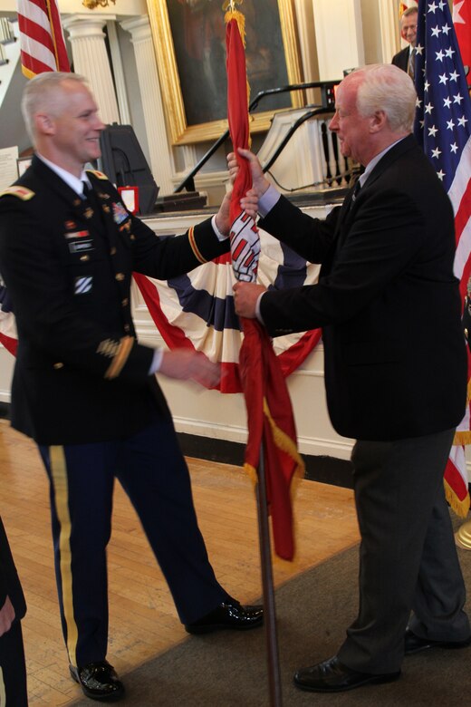 Col. Christopher Barron, district engineer and commander, U.S. Army Corps of Engineers New England District, passes the unit colors to Bill Scully, deputy district engineer, signifying the trust and confidence in the leaders of the organization at the change of command ceremony at Fanueil Hall, Boston, Mass.