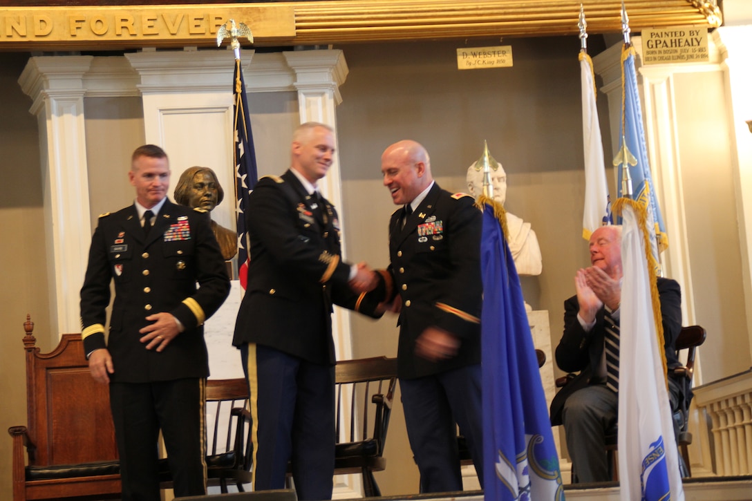 Col. Christopher Barron, district engineer, U.S. Army Corps of Engineers, New England District, shakes hands with Col. Charles Samaris, the district's outgoing commander, at the New England District Change of Command Ceremony at Faneuil Hall, Boston, Mass. Brig. Gen. Kent Savre (left), commander, U.S. Army Corps of Engineers, North Atlantic Division, presided over the ceremony, while Bill Scully (right), deputy district engineer, Project Management, New England District, claps.