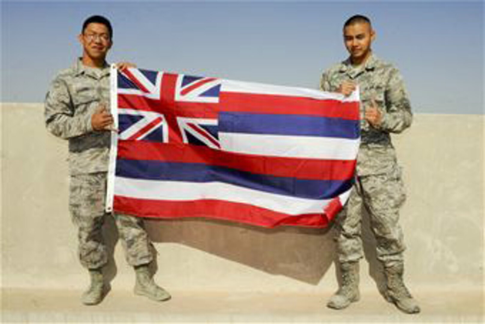 Senior Airman Ephesians Bagorio, and Airman 1st Class Kameron Combis, both from the 332nd Expeditionary Communications Squadron, hold the Hawaiian state flag at an undisclosed location in Southwest Asia, Jan. 20, 2012. Bagorio and Combis graduated together from Barber's Point Campus of the Hawaii National Guard's Youth Challenge Academy. The academy is a program that helps misguided youth to become a working part of the community. Bagorio is deployed from Davis-Monthan Air Force Base, Ariz., and Combis is deployed from the Hawaii Air National Guard. Both are natives of the state of Hawaii.