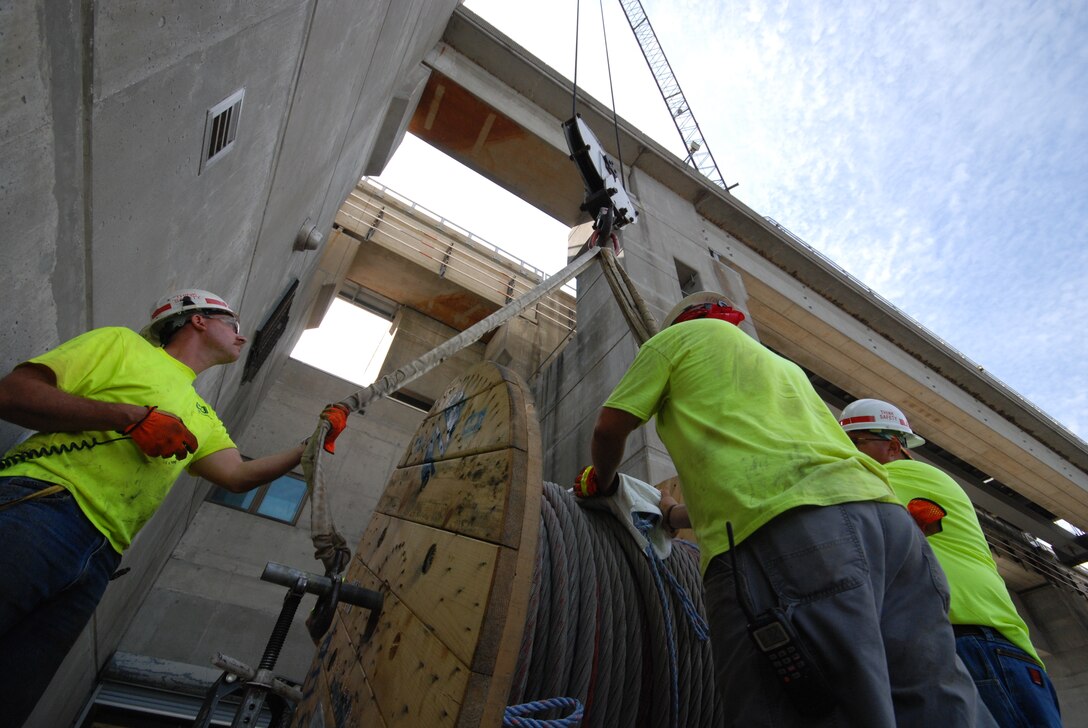 Lock crews from the St. Louis District guide a cable spool into position prior to installing the cables on the upstream lift gate of the main lock chamber at Mel Price Locks and Dam.