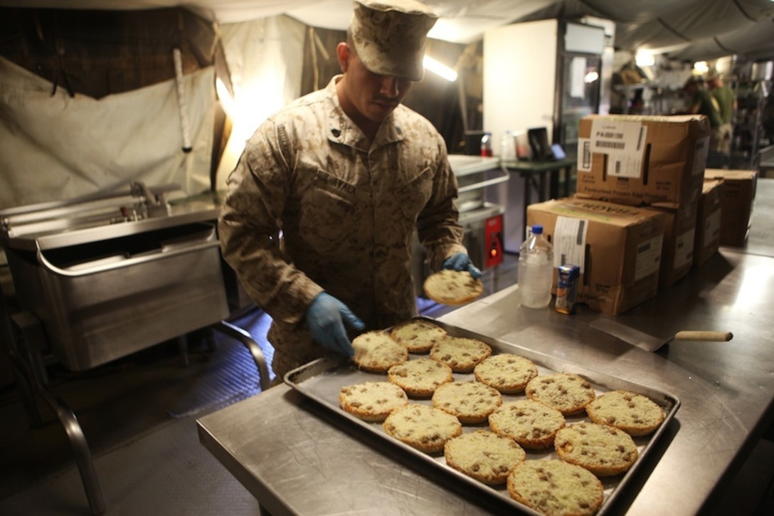 Sergeant Eduardo Ayala, a food service specialist with 1st Battalion, 7th Marine Regiment, prepares miniature pizzas at the Harvest Falcon dining facility for the dinner rush aboard Camp Dwyer, Helmand province, Afghanistan, July 21, 2014. The food service Marines at Harvest Falcon are in charge of making sure meals are served at the correct temperature, the facility is cleaned daily and food is cooked properly for every meal. (U.S. Marine Corps photo by Cpl. Cody Haas/ Released)