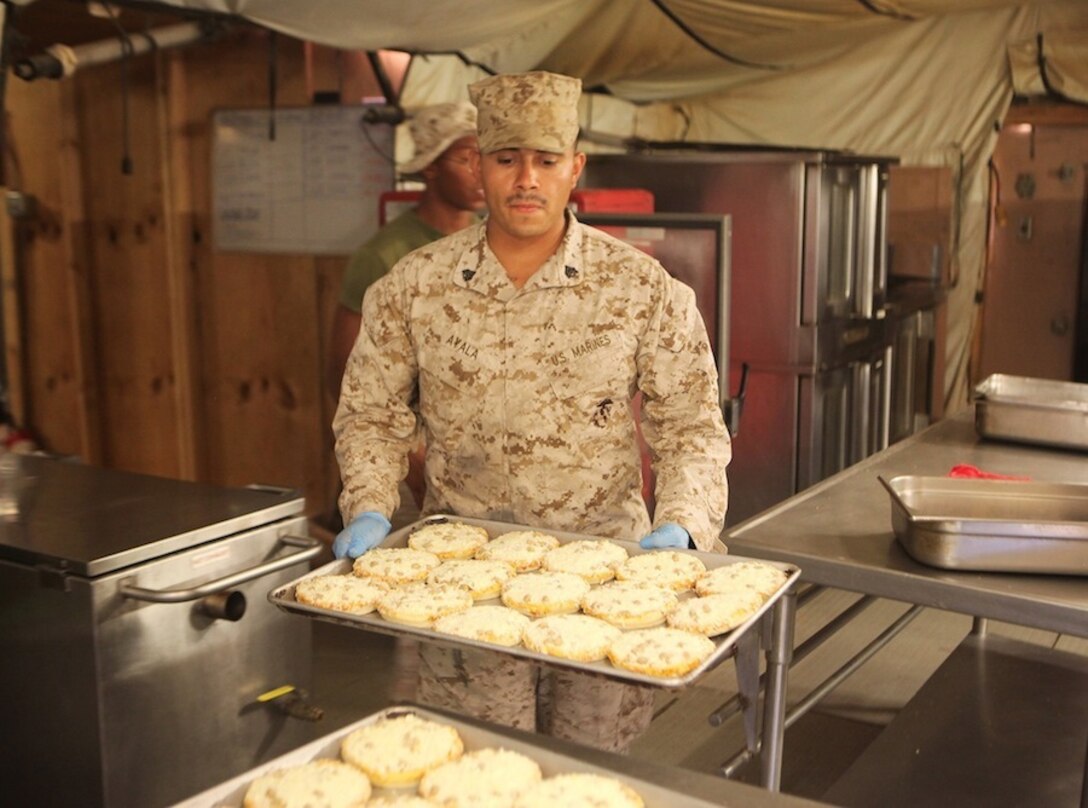 Sergeant Eduardo Ayala, a food service specialist with 1st Battalion, 7th Marine Regiment, prepares miniature pizzas at the Harvest Falcon dining facility for the dinner rush aboard Camp Dwyer, Helmand province, Afghanistan, July 21, 2014. The food service Marines at Harvest Falcon are in charge of making sure meals are served at the correct temperature, the facility is cleaned daily and food is cooked properly for every meal. (U.S. Marine Corps photo by Cpl. Cody Haas/ Released)