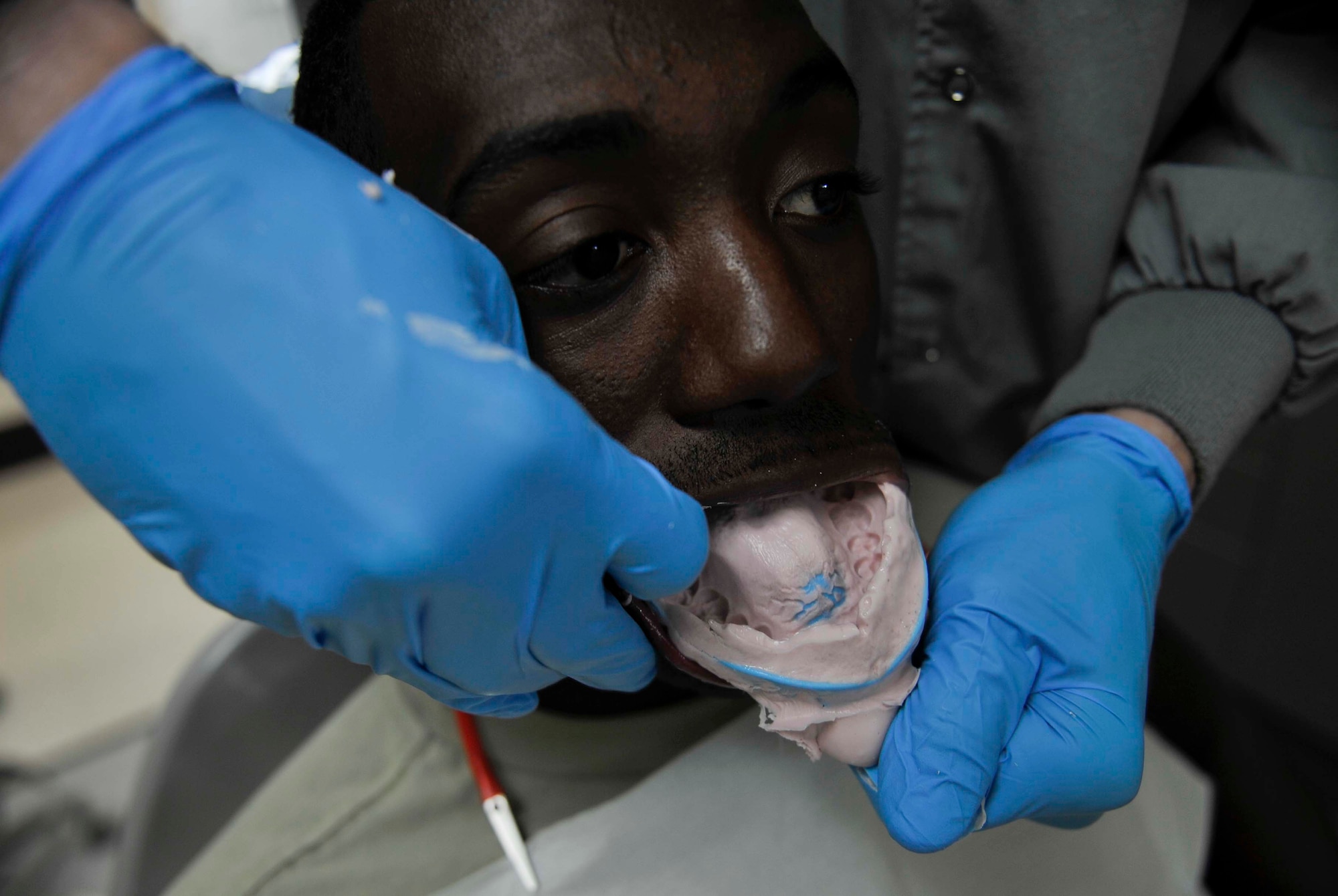 Dr. Ryan Gustafson, 51st Dental Squadron general dentist, pulls a tooth impression out of Senior Airman Keiyon Monroe, 51st DS dental technician, to make a mouth guard on Osan Air Base, Republic of Korea, July 31, 2014. The dental lab makes two types of mouth guards: sports guards and night guards. (U.S. Air Force photo/Senior Airman David Owsianka)