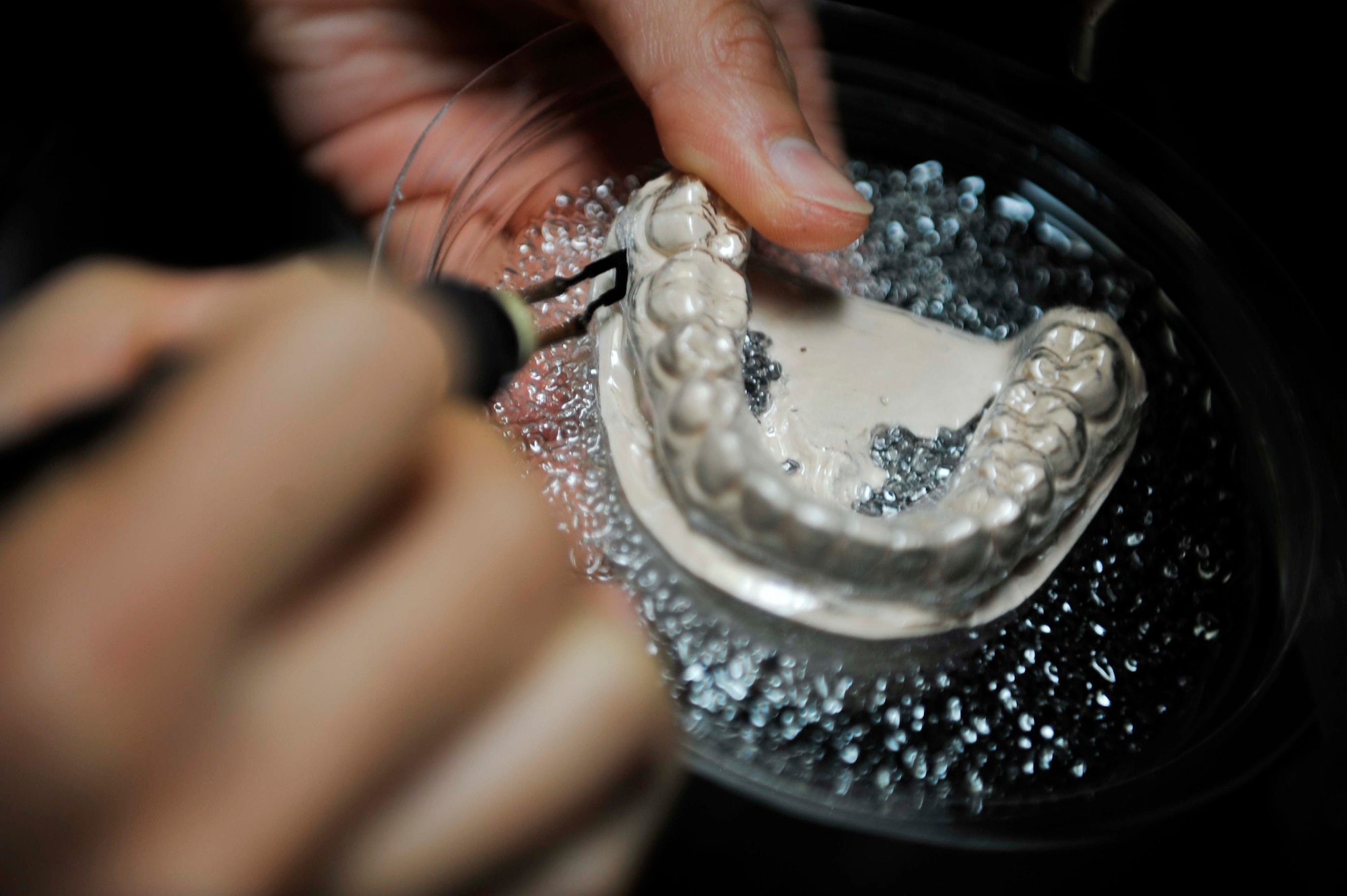 Staff Sgt. Janine Sung, 51st Dental Squadron laboratory technician, uses a hot knife to cut the essix material off of a mouth guard cast on Osan Air Base, Republic of Korea, July 29, 2014. The dental laboratory flight fabricates fixed and removable dental prostheses, including individual crowns, hard night guards, interim removable partial dentures and retainers. (U.S. Air Force photo/Senior Airman David Owsianka)